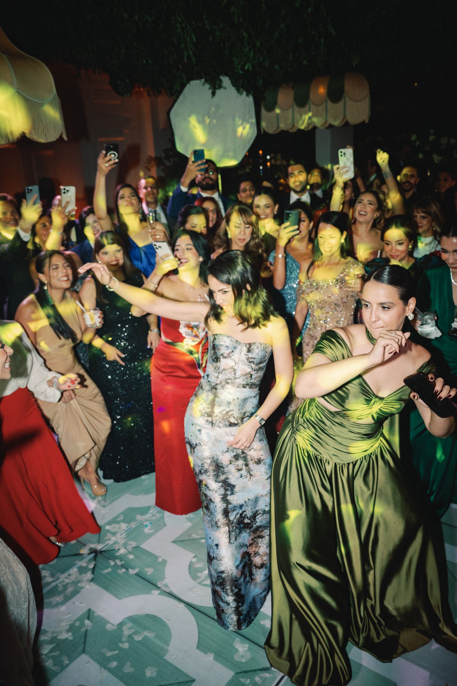 Dancers in formal attire move energetically on a crowded dance floor at a celebration event.
