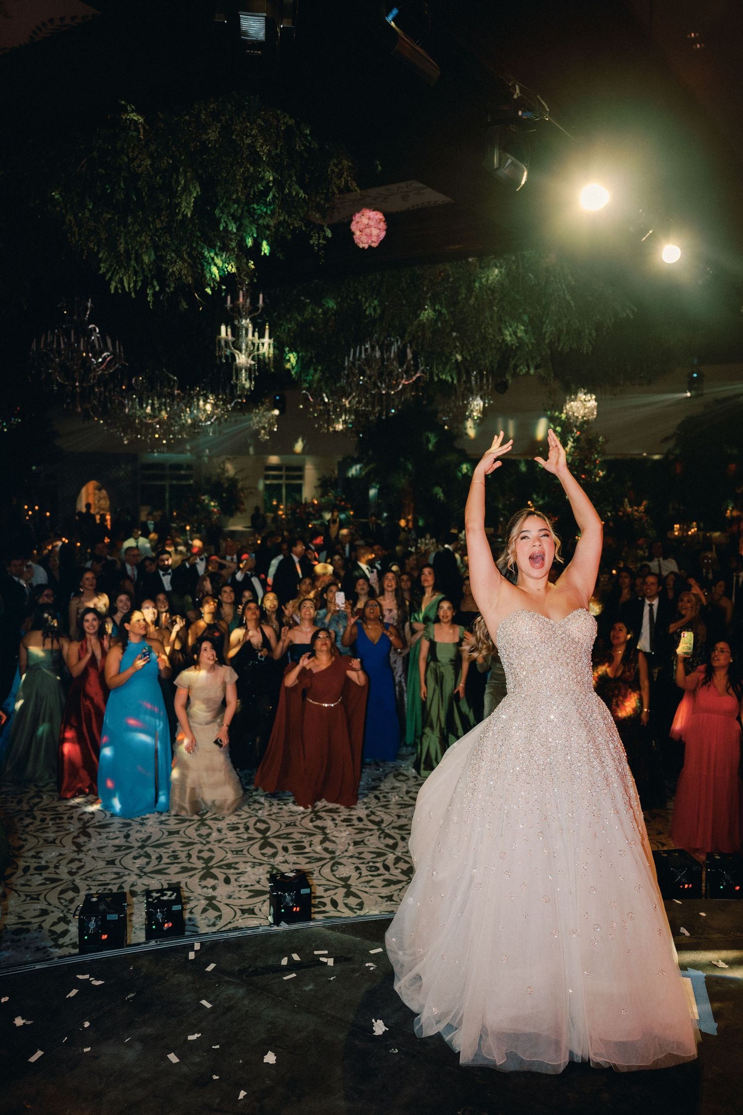 A group of party guests dancing at a nighttime celebration with a person in a white ballgown as the focal point.