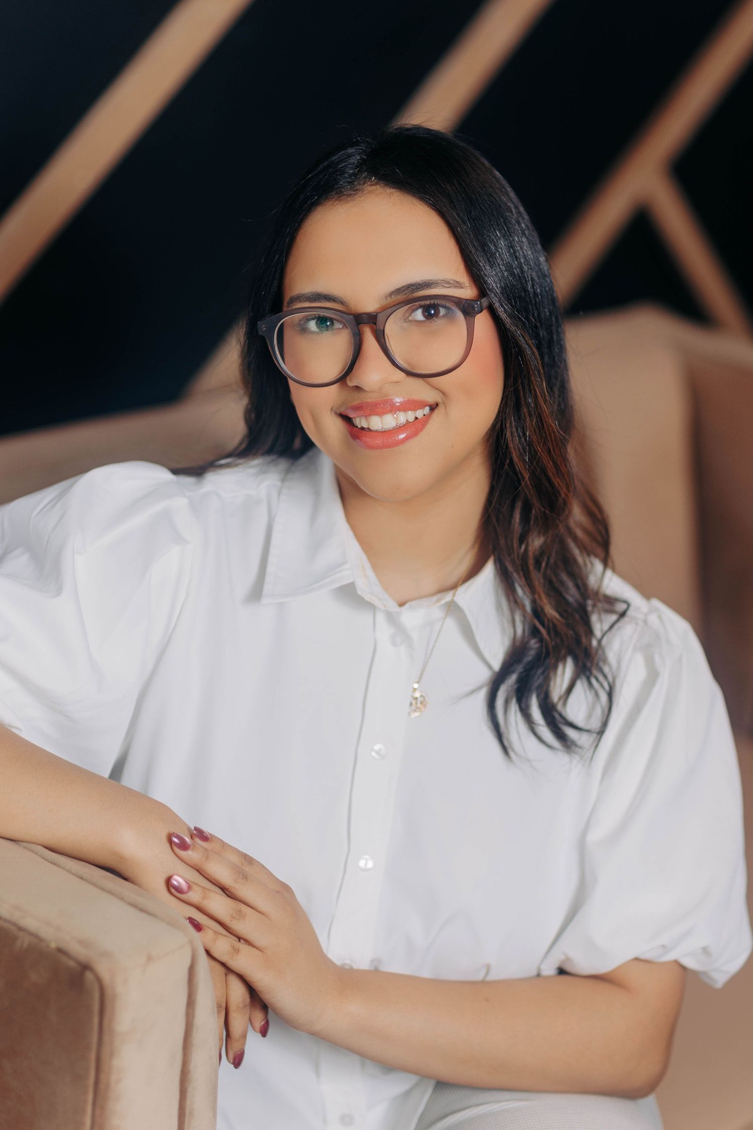Professional headshots in white button-down shirt with glasses against dark background.
