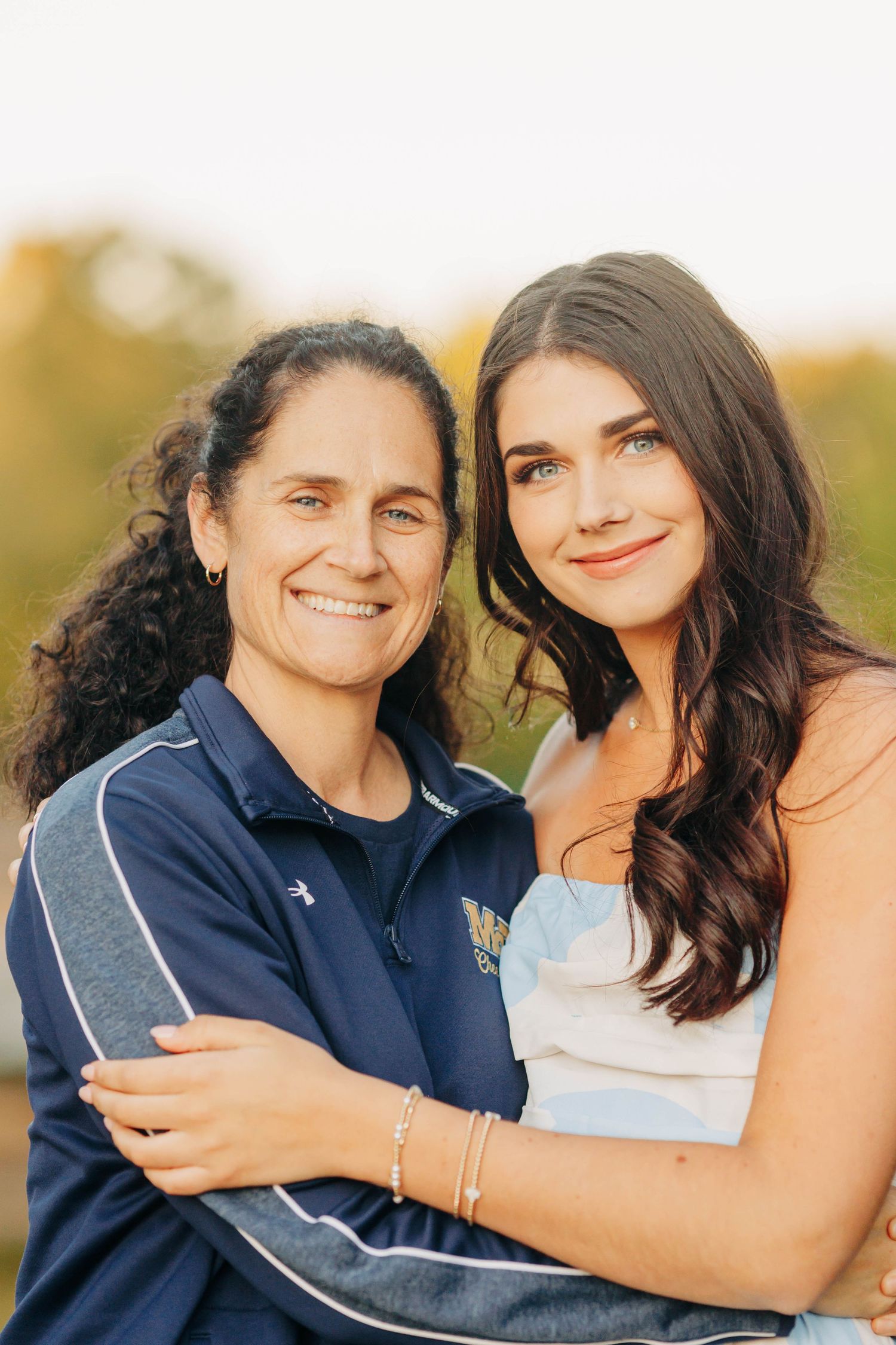 Mother and daughter embrace during outdoor sunset portrait session.