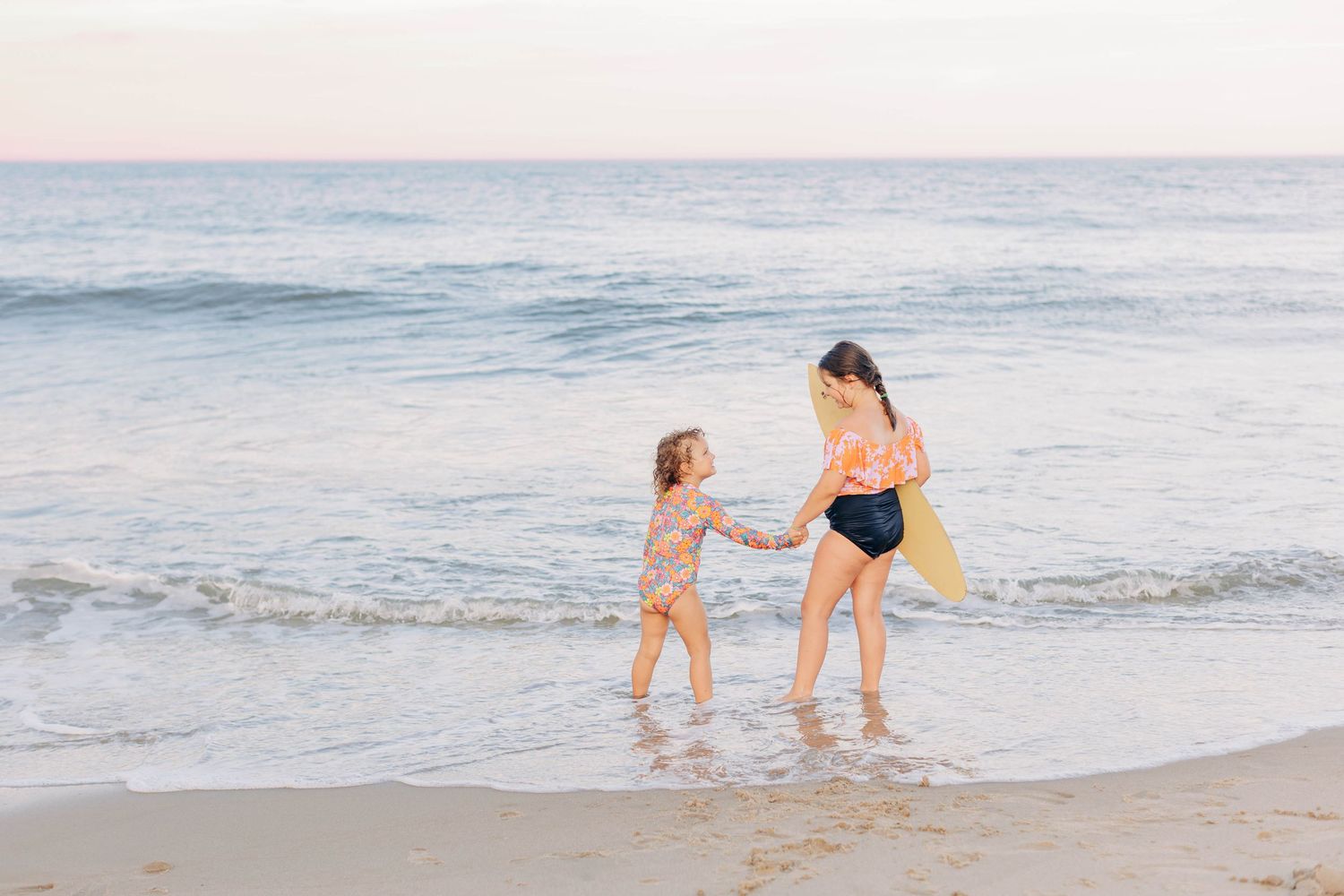 Family playing together at the beach during sunset with waves in background.