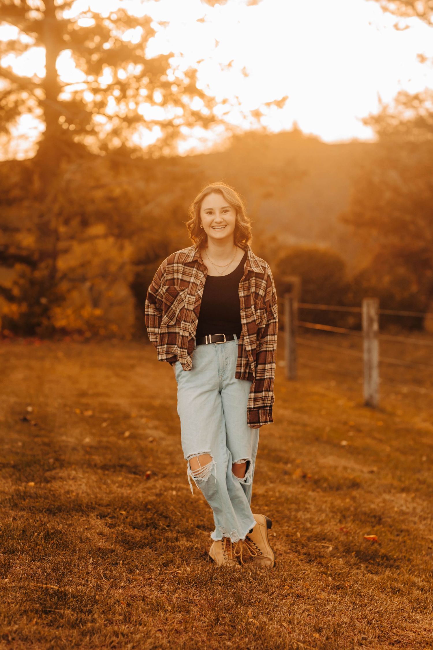 Casual autumn portrait in plaid shirt and distressed jeans during golden hour.