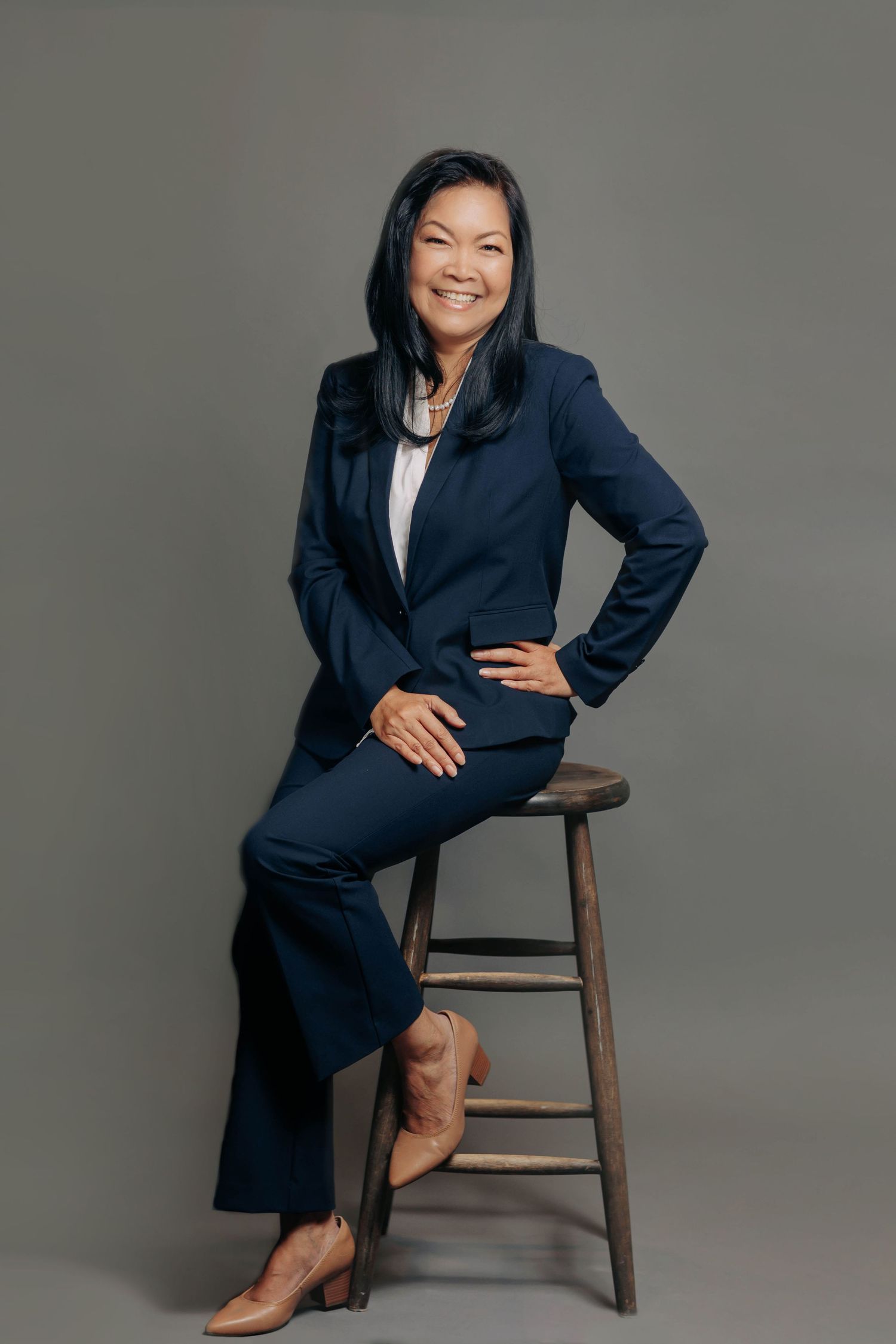Professional portrait series showing different poses on wooden stool against gray background.