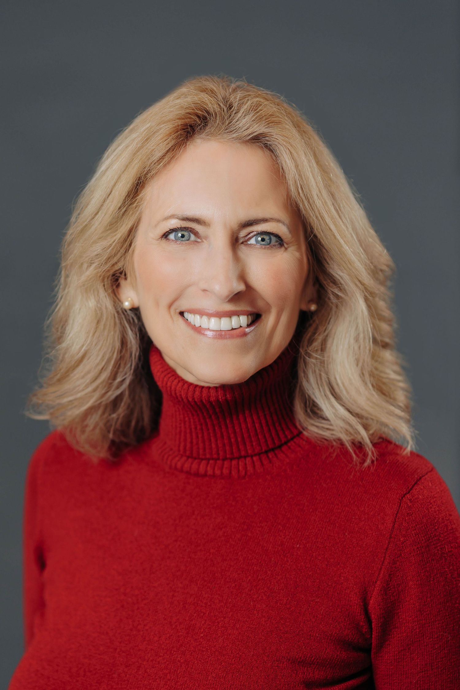 Warm portrait series featuring red turtleneck sweater against dark gray backdrop.
