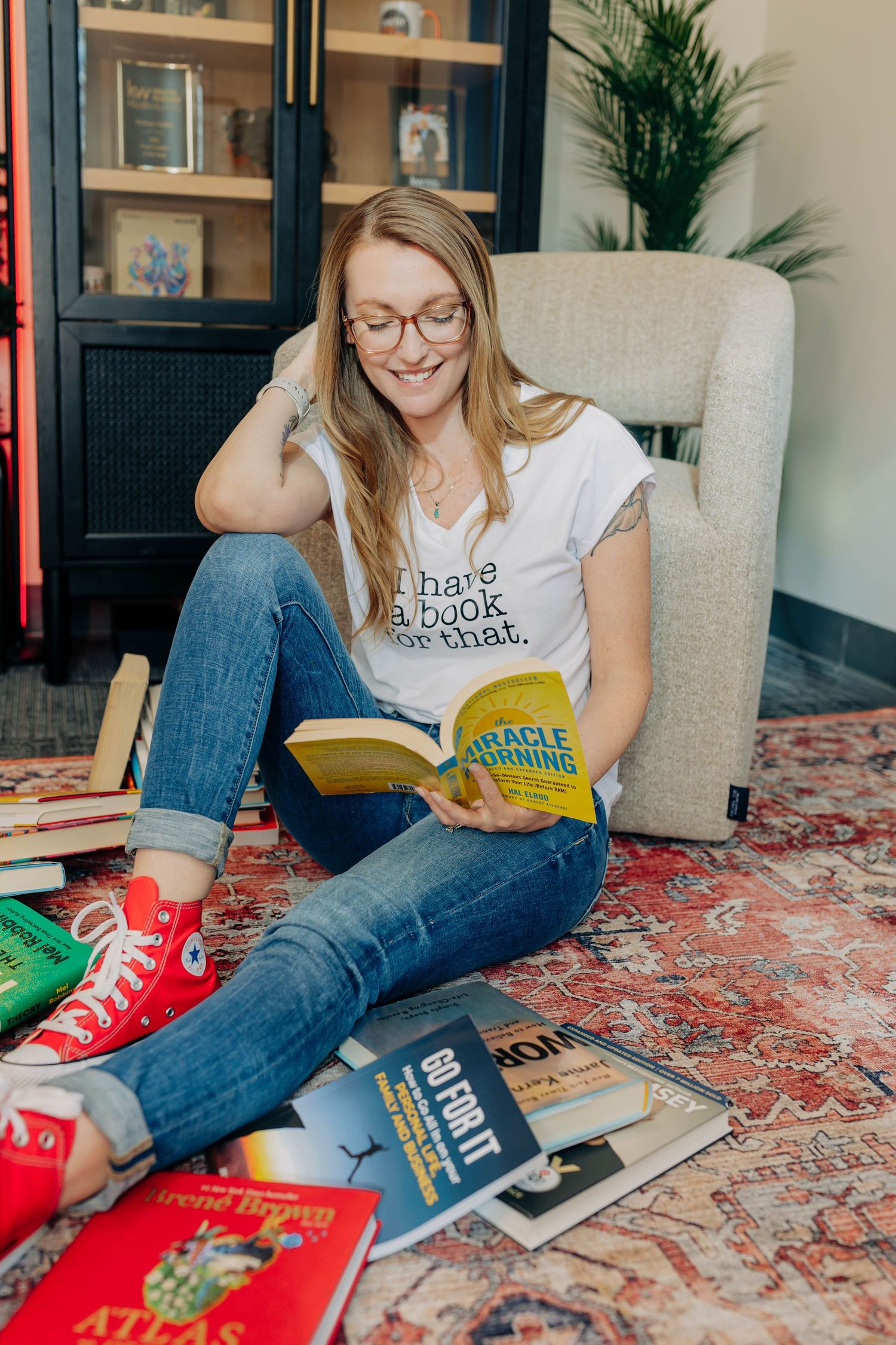 Reading session with books scattered on patterned rug featuring red sneakers.