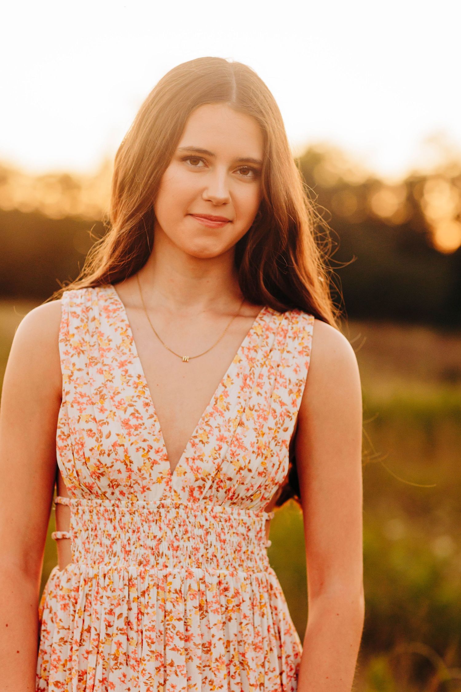Floral sundress glows in warm sunset light during outdoor portrait session.