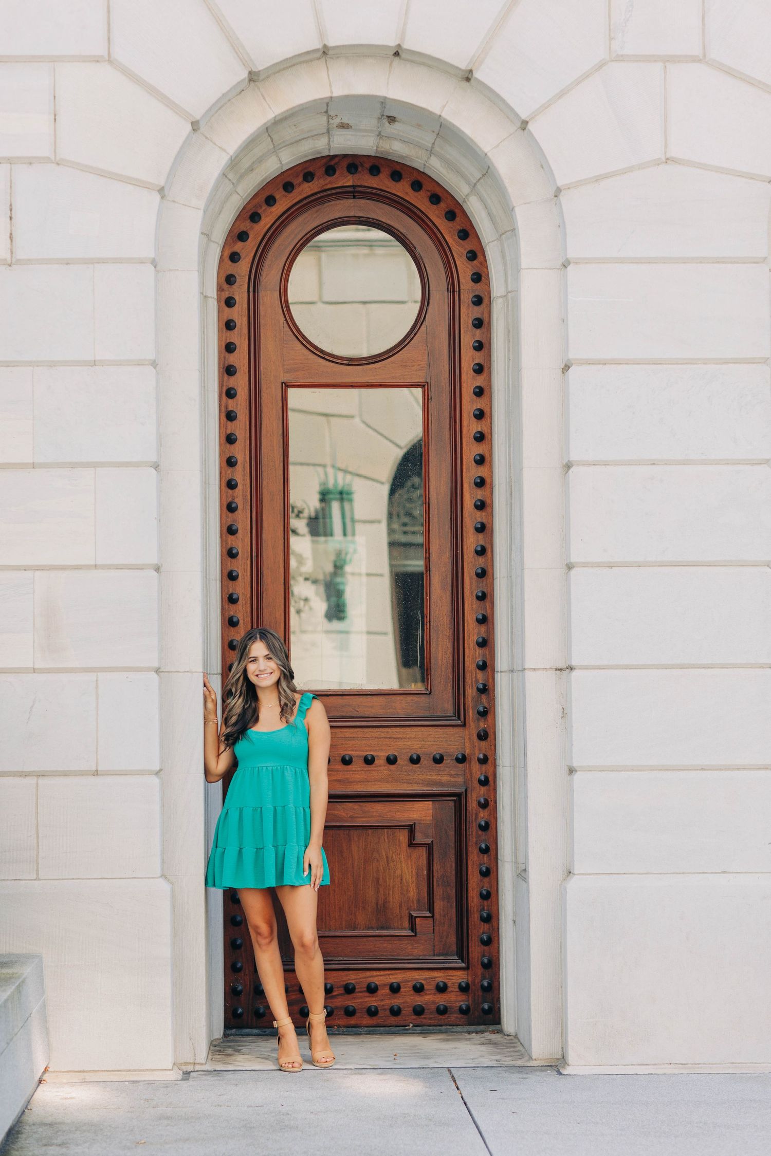 Person in turquoise dress standing in ornate wooden doorway of historic building.