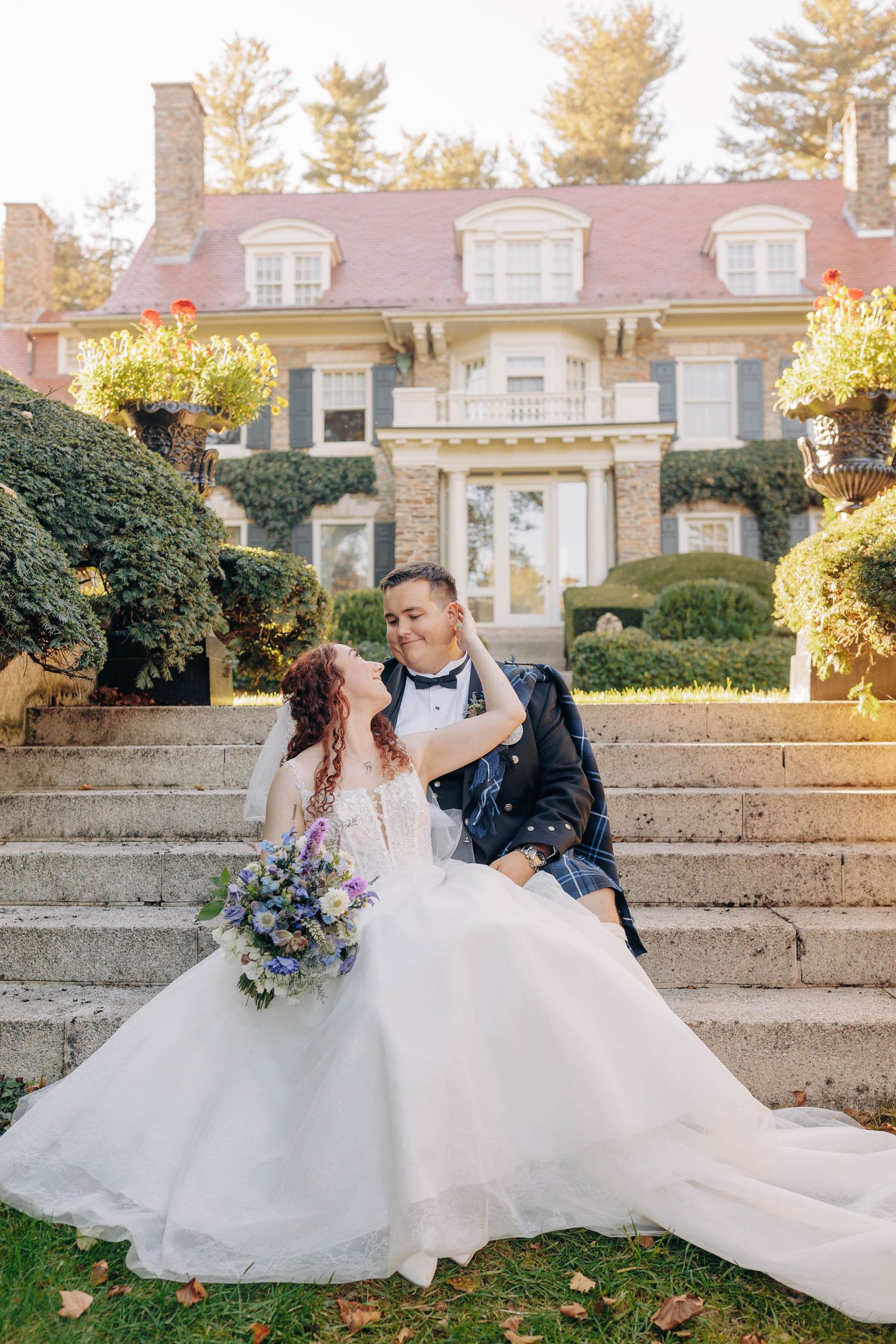 A romantic wedding portrait on stone steps with elegant landscaping in the background.