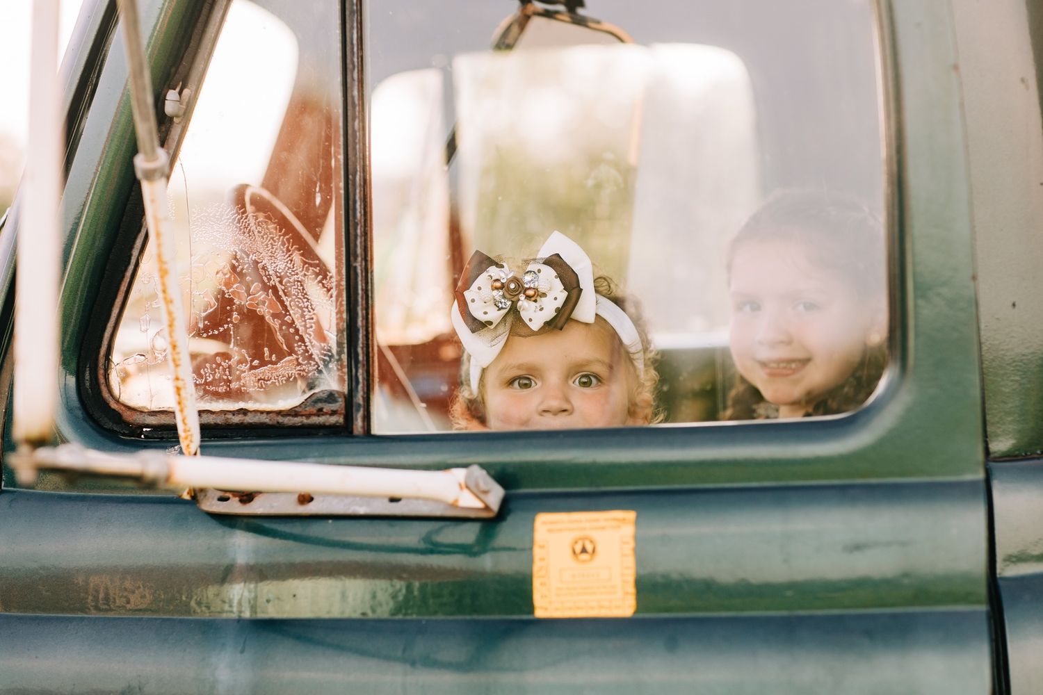 Vintage green truck window with wedding rings visible in reflection.