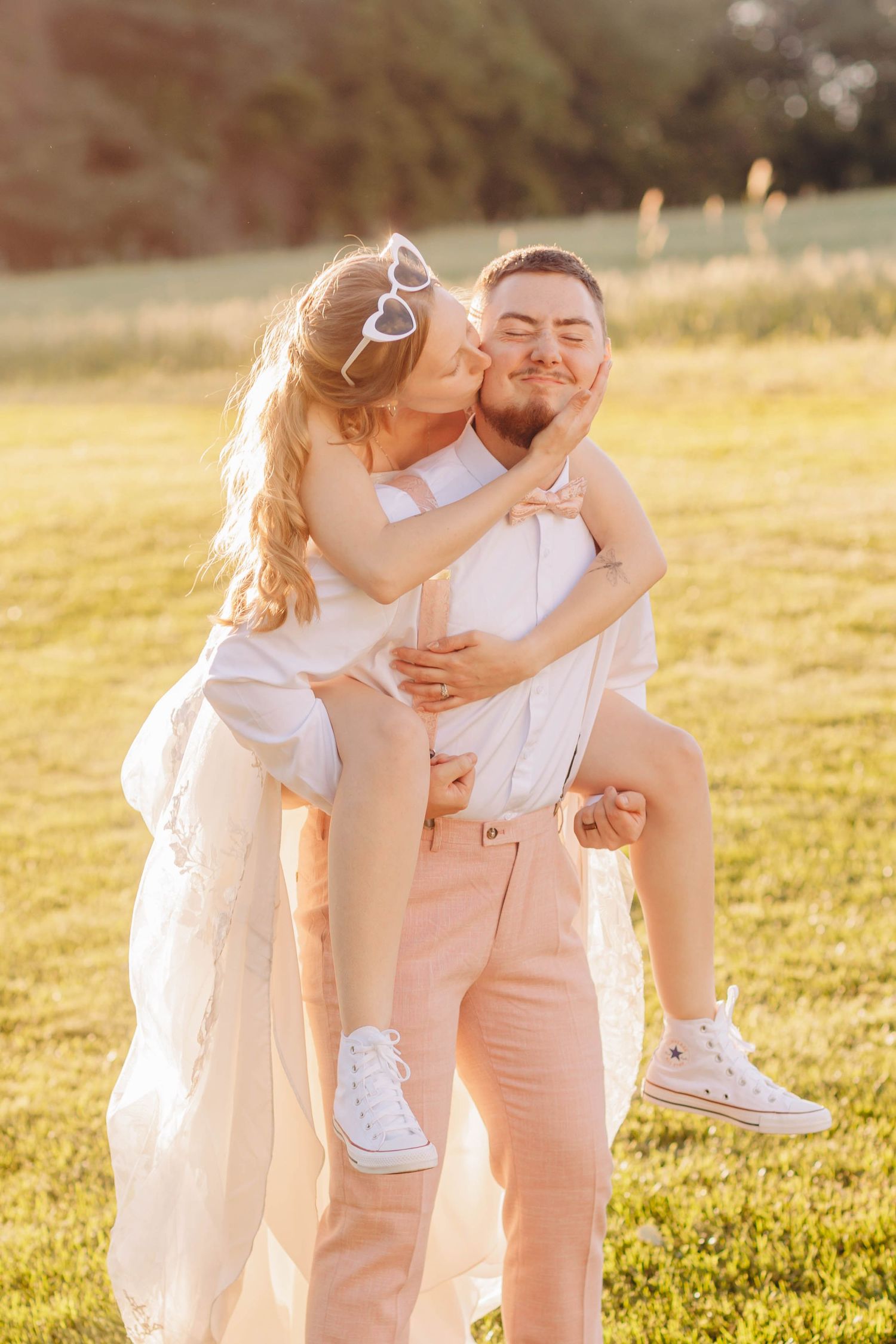 A romantic golden hour photoshoot in a sunlit field with soft lighting and elegant attire.