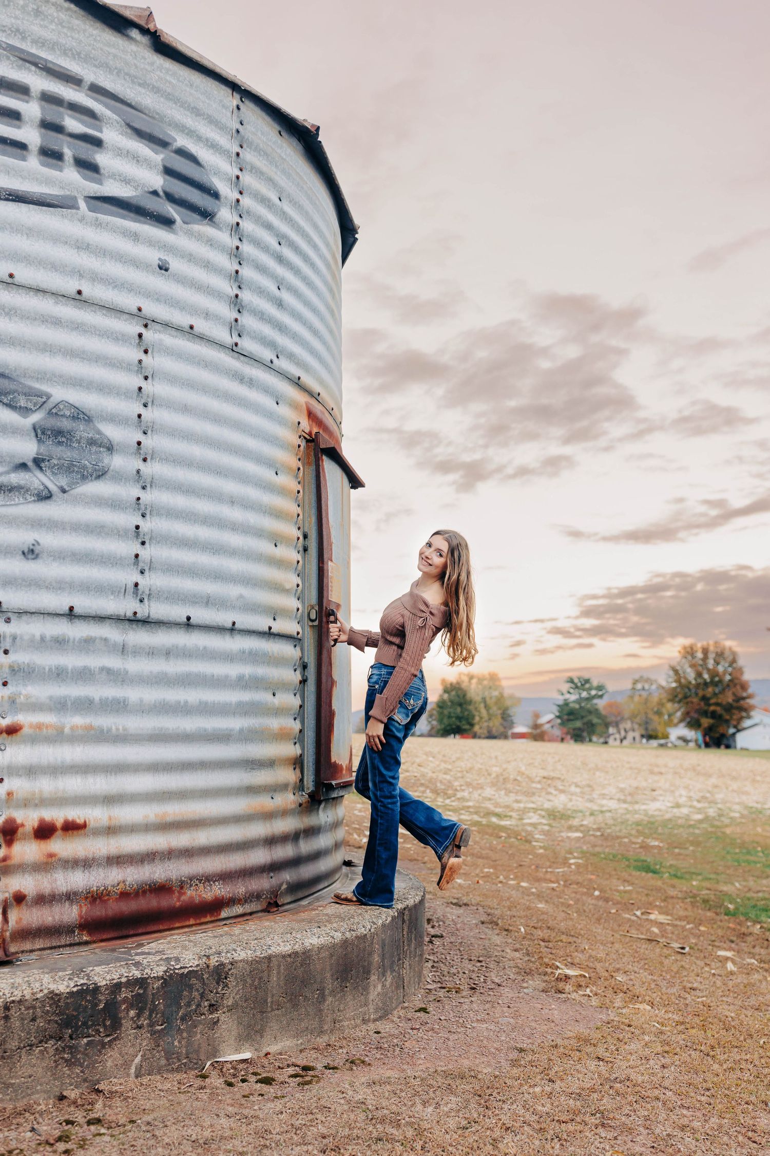 Artistic photoshoot against a rustic grain silo with dramatic evening sky.