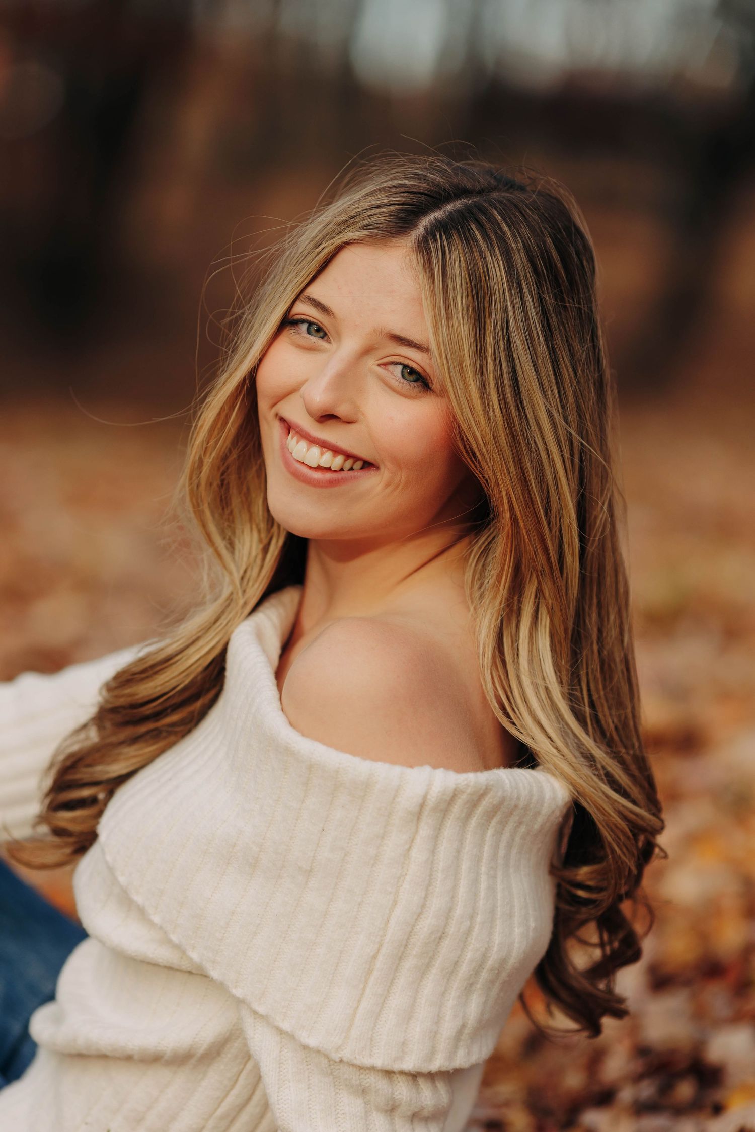 Person in a cream turtleneck sweater against a warm autumn background.