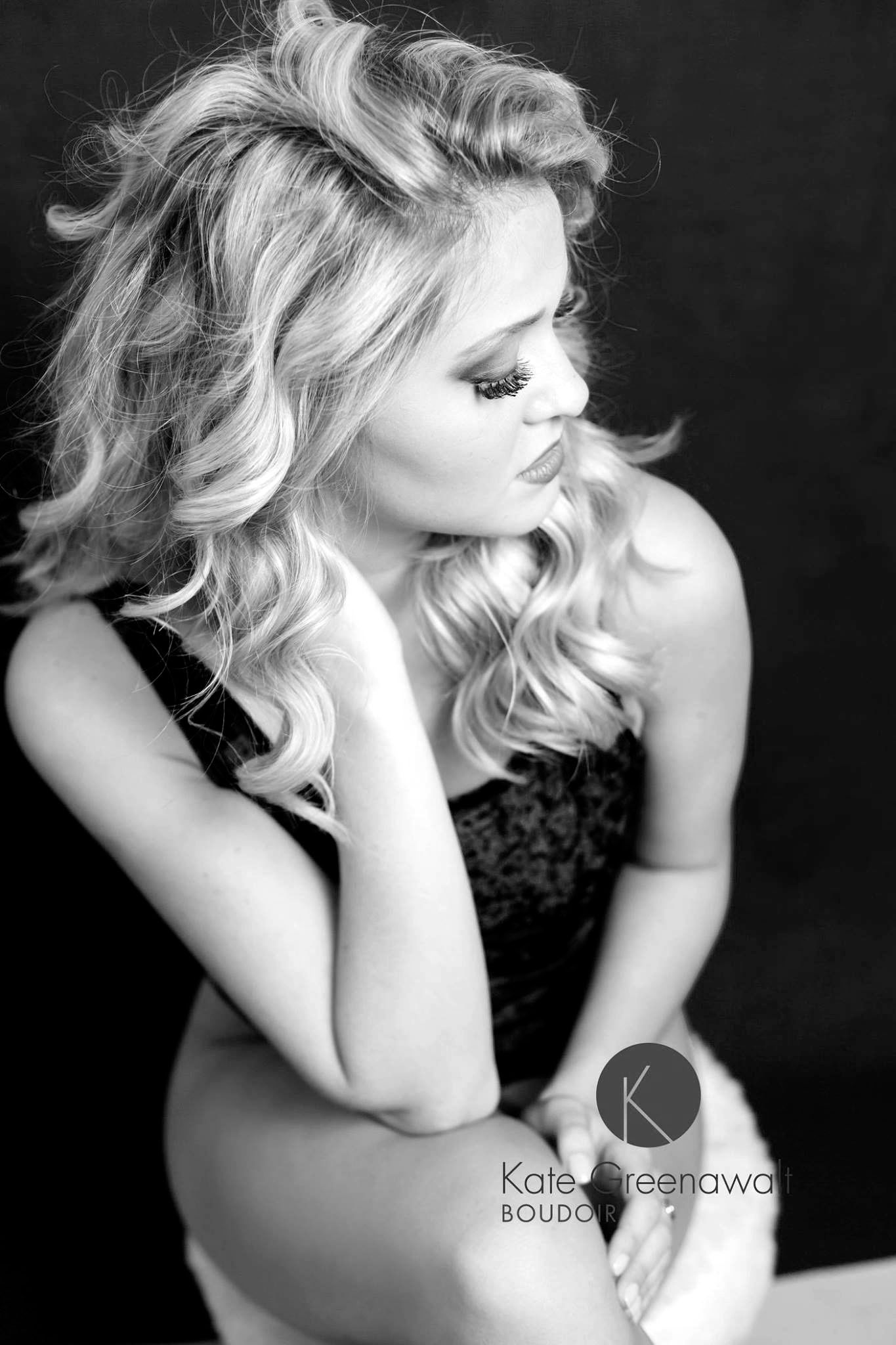 Dramatic black and white portrait with soft lighting and styled blonde waves.