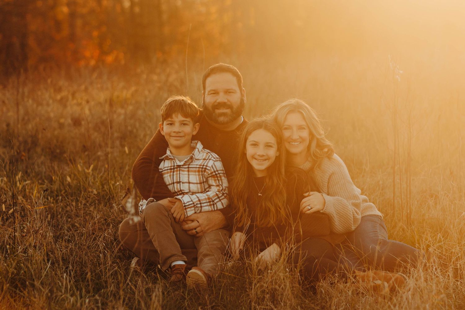 Family portrait session during golden hour in a rustic outdoor setting.