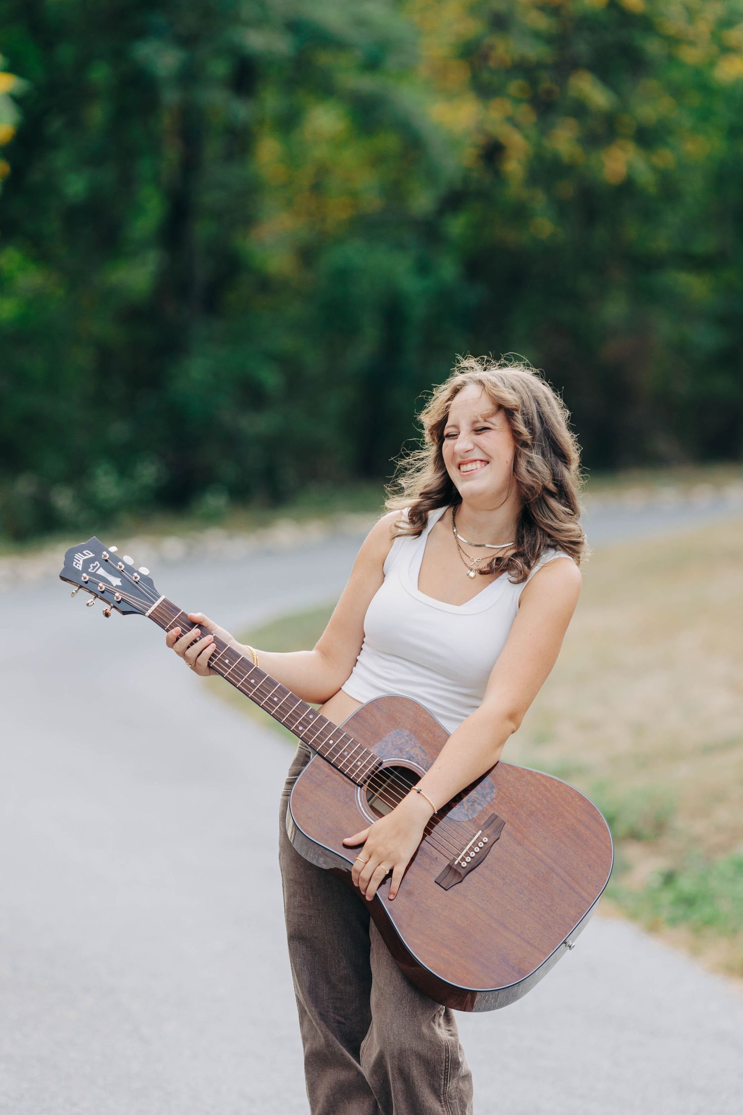 Joyful outdoor music session with acoustic guitar in a natural setting.