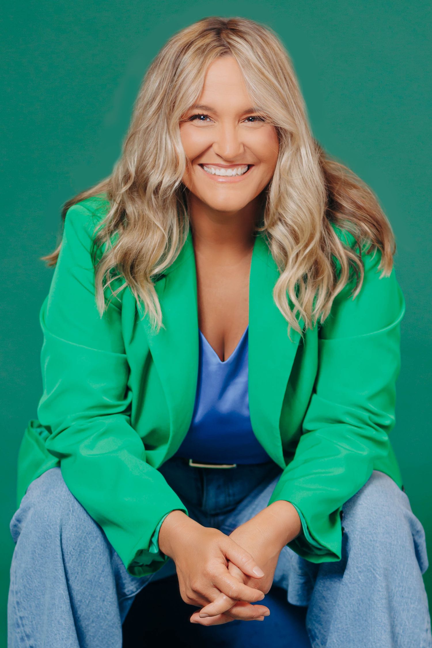 Stylish green blazer and denim outfit captured in multiple poses against emerald backdrop.