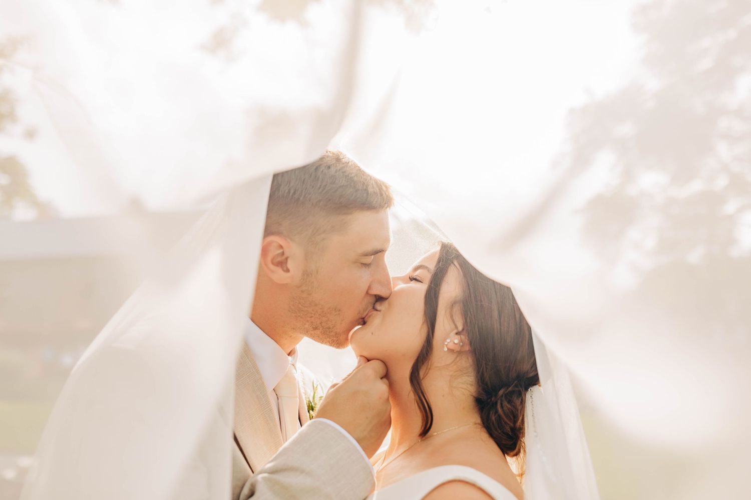 Romantic wedding portrait with soft white veil and dreamy lighting.