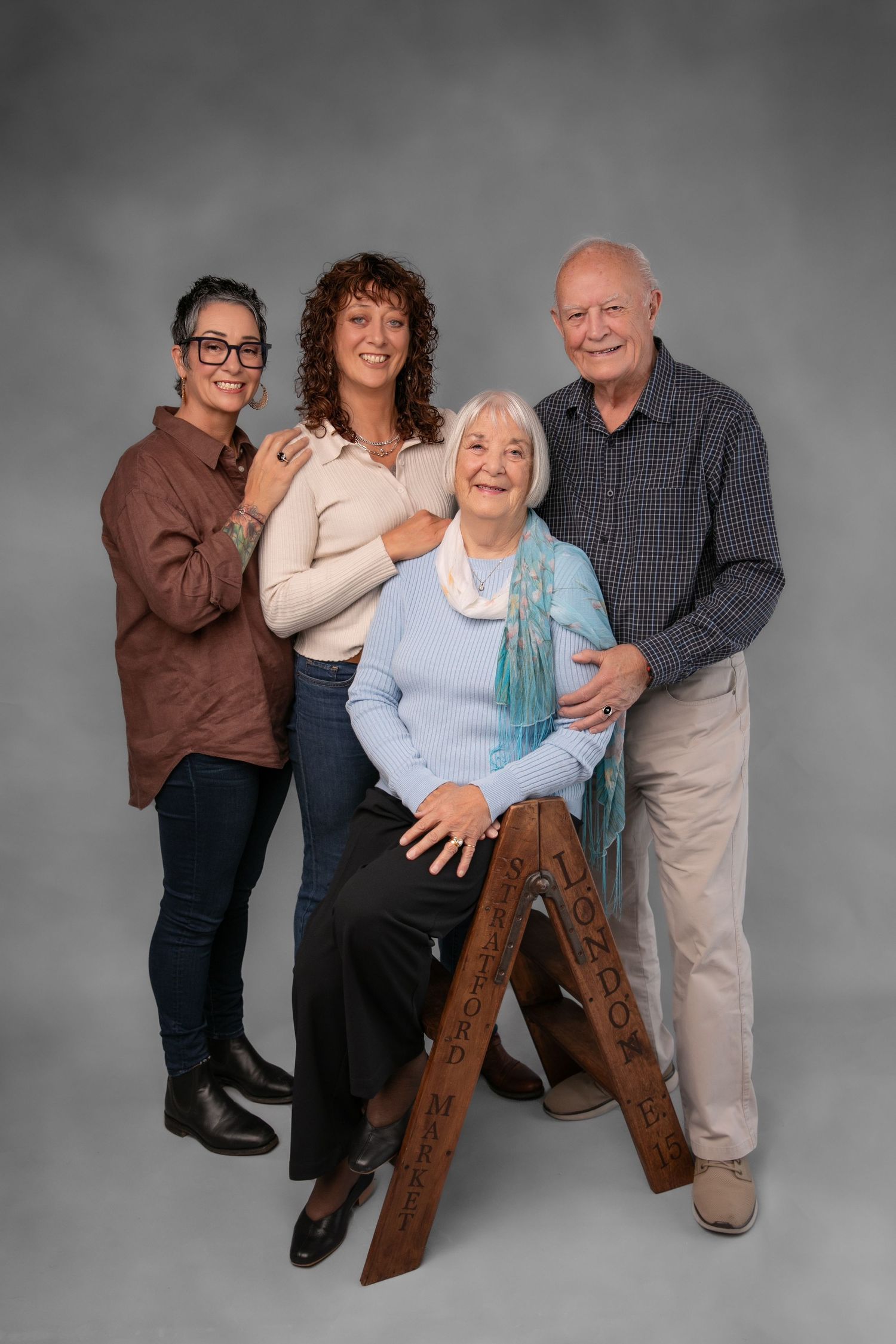 A playful family portrait series showing three people posing and laughing together against a gray studio backdrop.