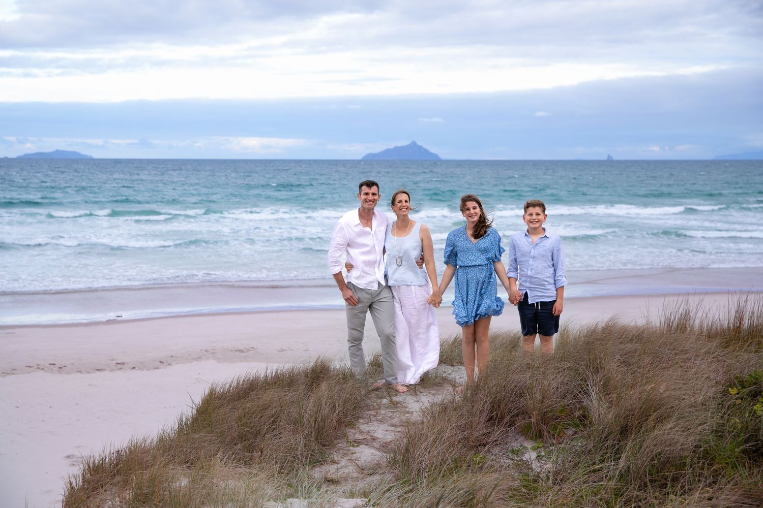 A series of coastal beach scenes with sand dunes, ocean waves, and people walking along the shoreline on a cloudy day.