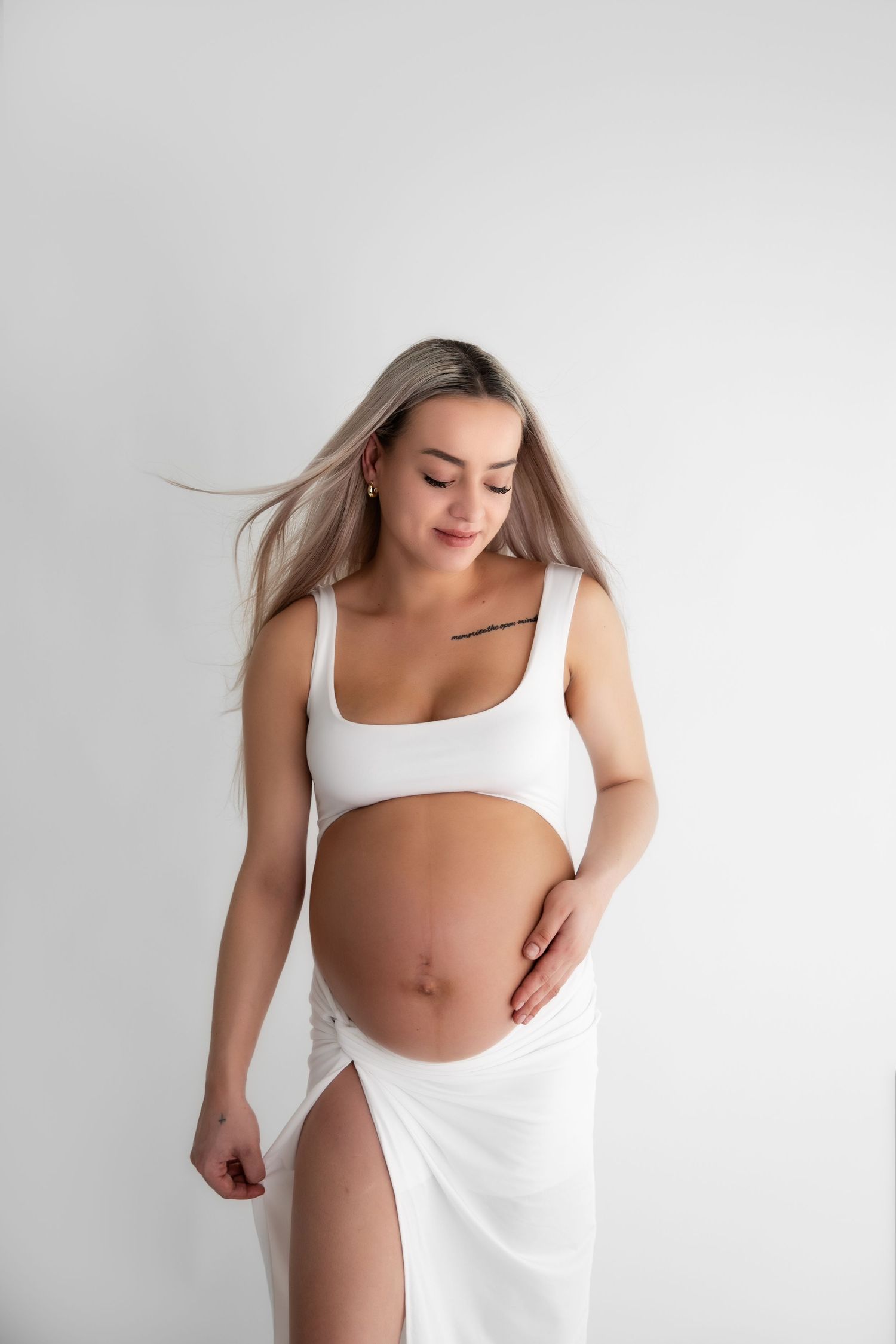 Artistic maternity photo series showing a pregnant figure in white against a light background.