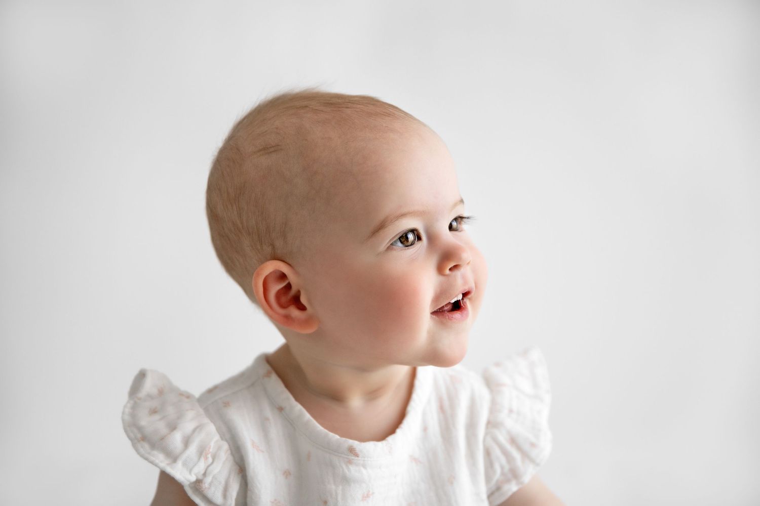 A series of six black and white photos showing a baby in white clothing looking upward with joyful expressions.