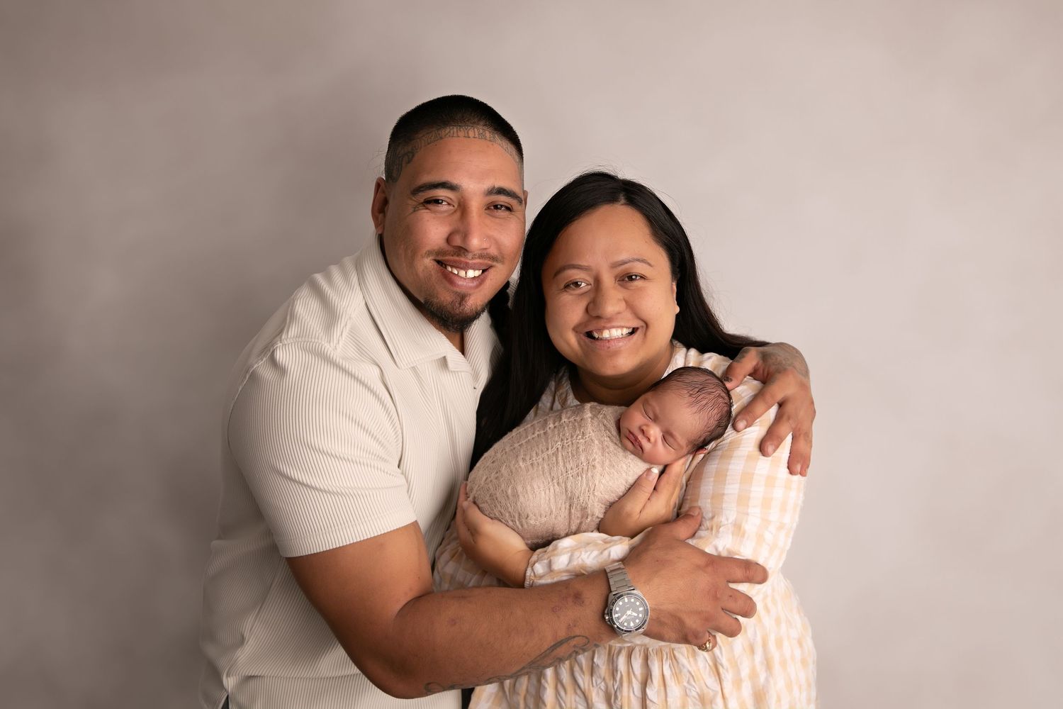 A couple wearing white sits together in a series of intimate portrait poses against a neutral background.