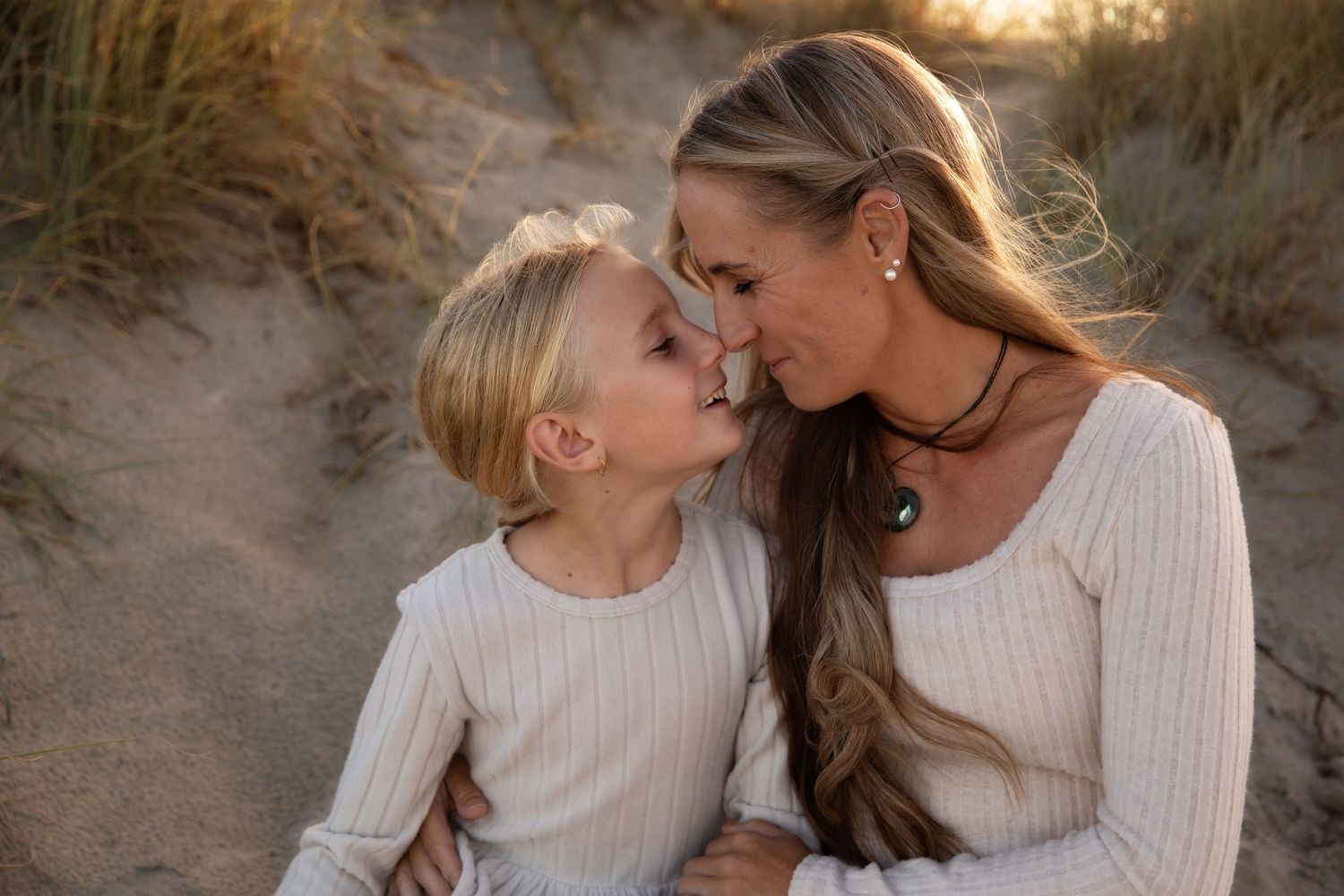 A series of intimate beach portraits showing tender moments between two people at sunset among sandy dunes.