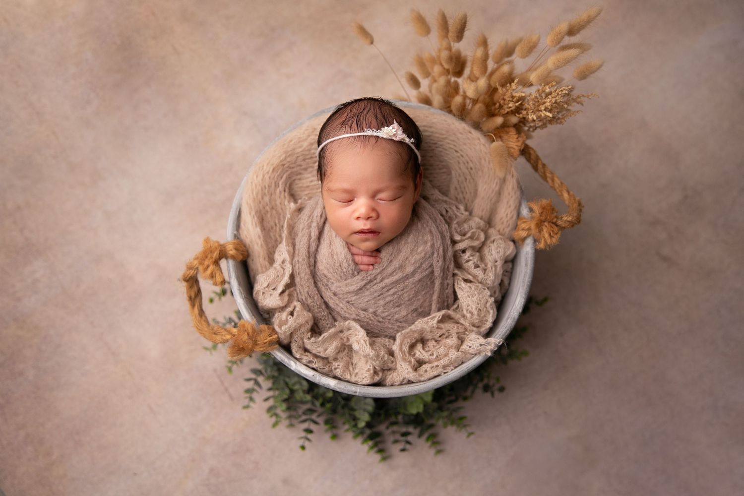 A collection of seven newborn photography images showing a sleeping baby in various neutral-toned poses with floral accents.