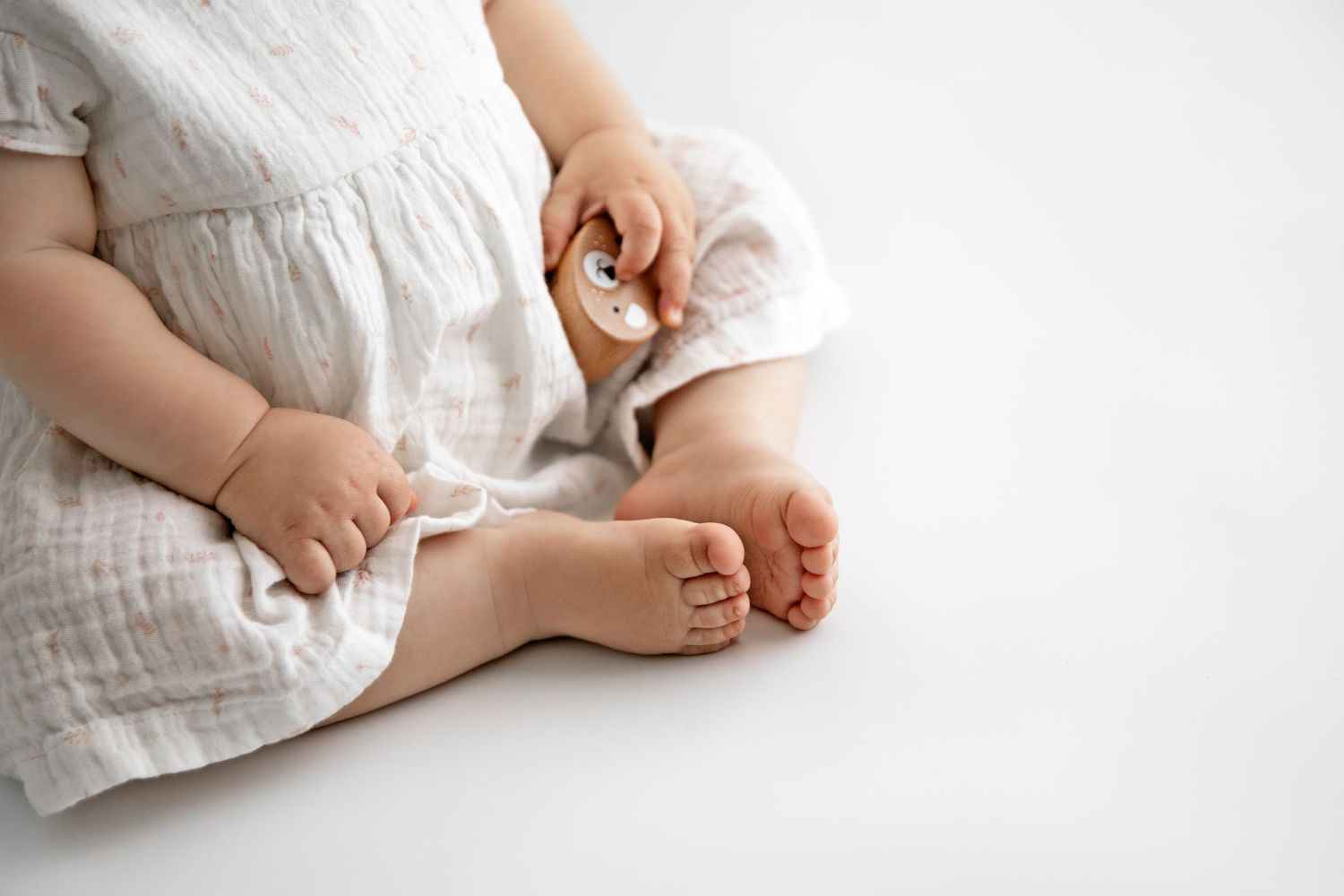 Close-up view of tiny baby feet wrapped in soft white muslin fabric against a light background.