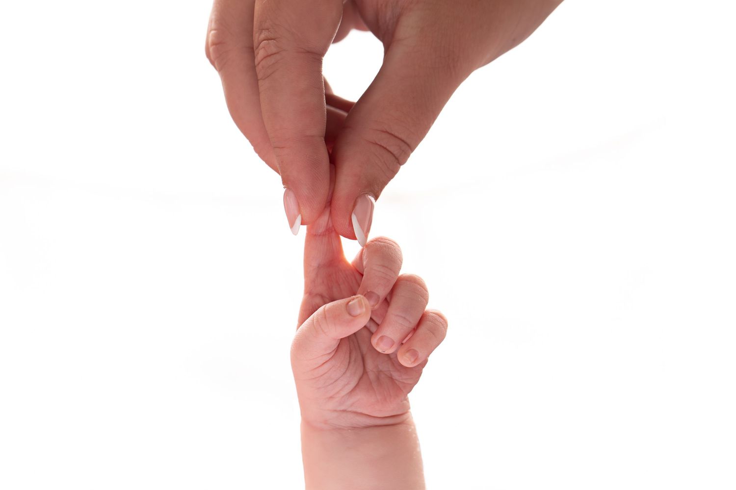Four hands hold up a small pink newborn baby sock against a white background.