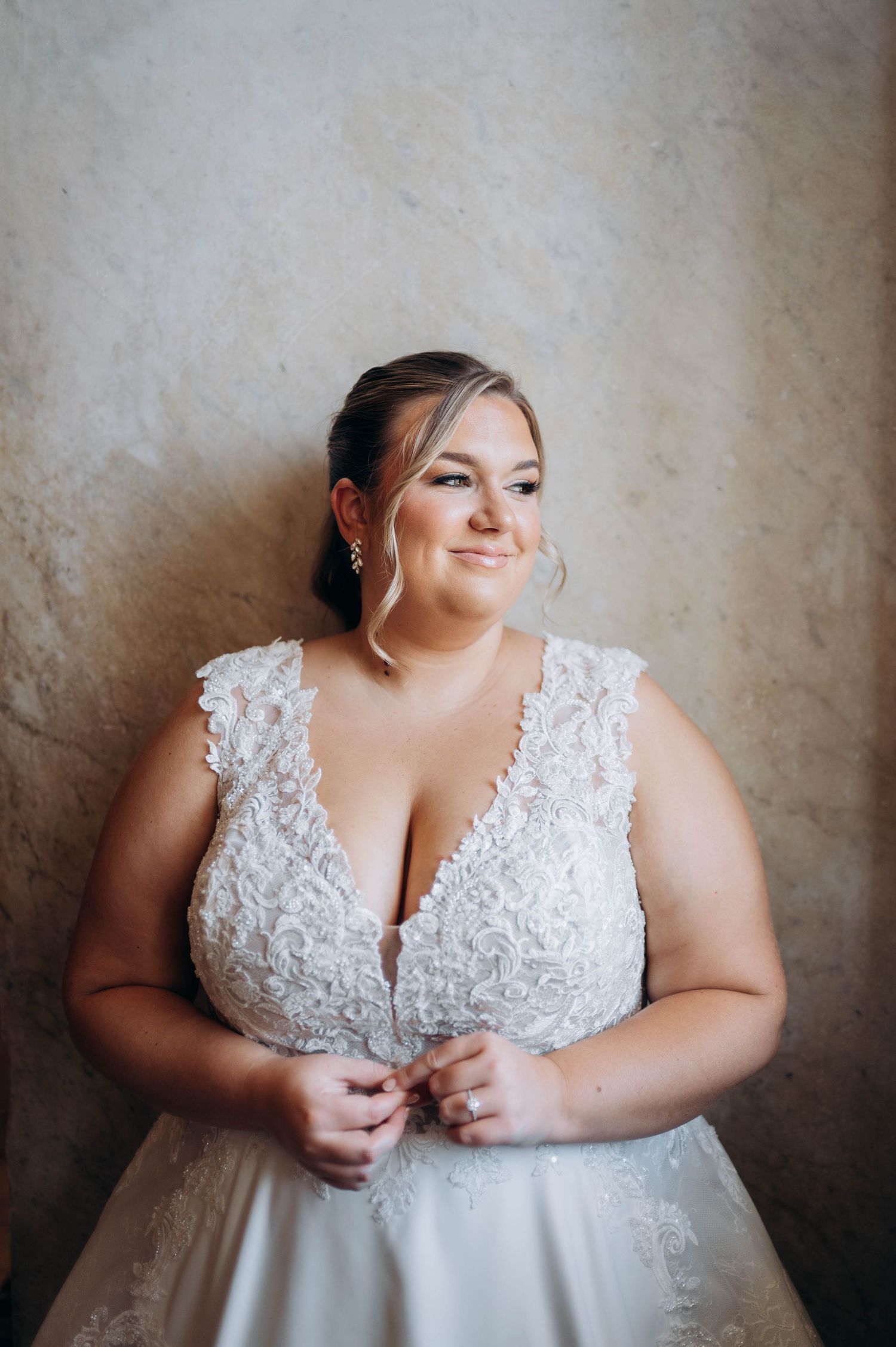 Close-up bridal portrait showcasing intricate lace bodice details against neutral background.