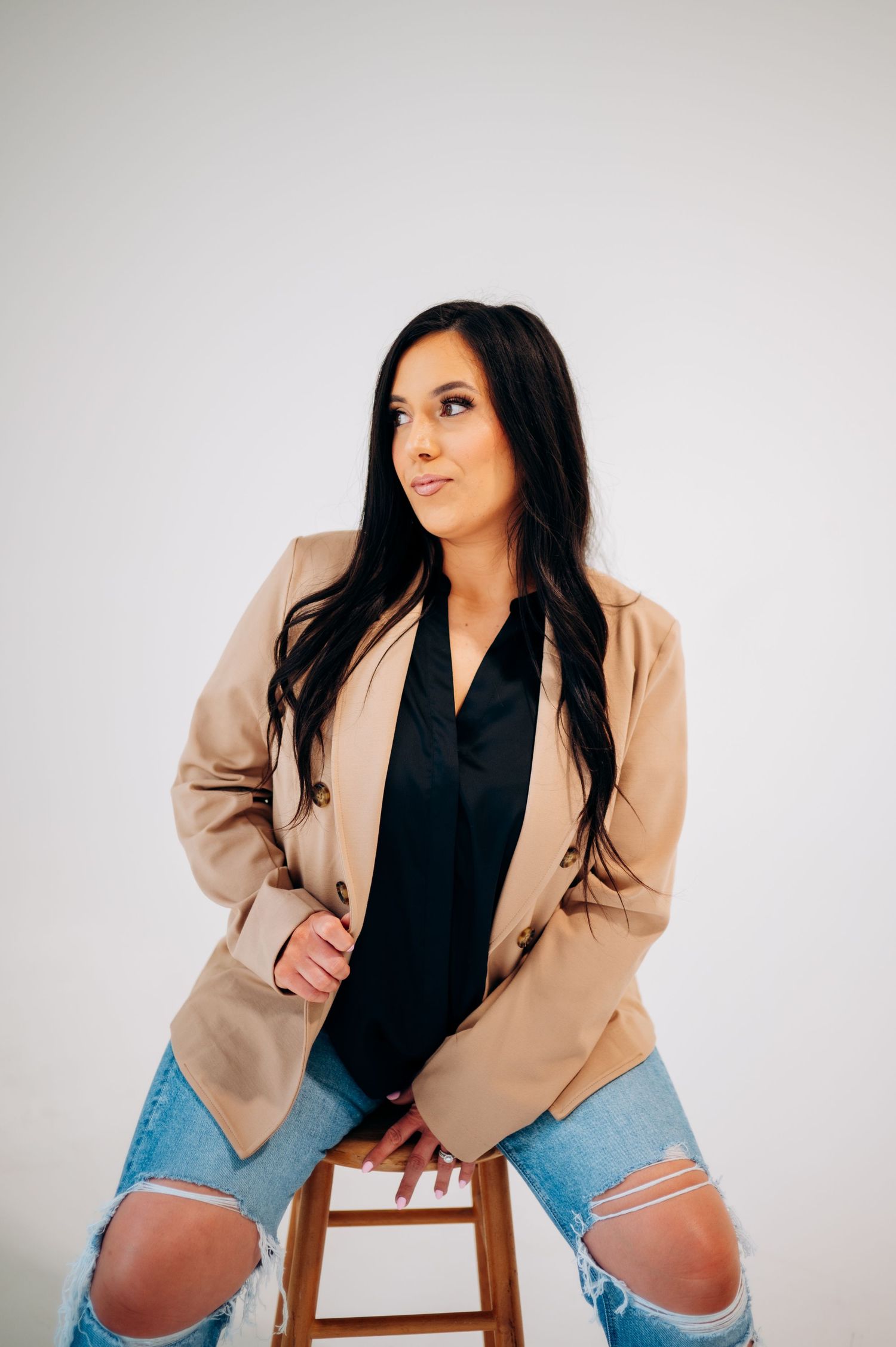 Modern casual look with beige blazer and distressed denim in studio setting.