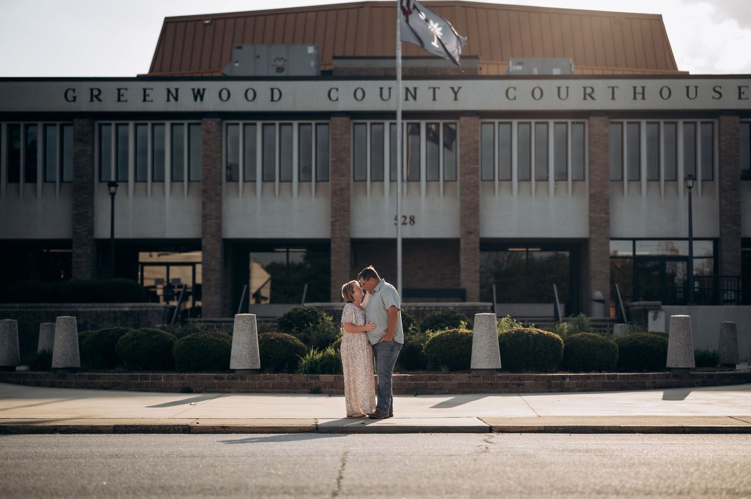 Couple embracing in front of Greenwood County Courthouse on their wedding day.