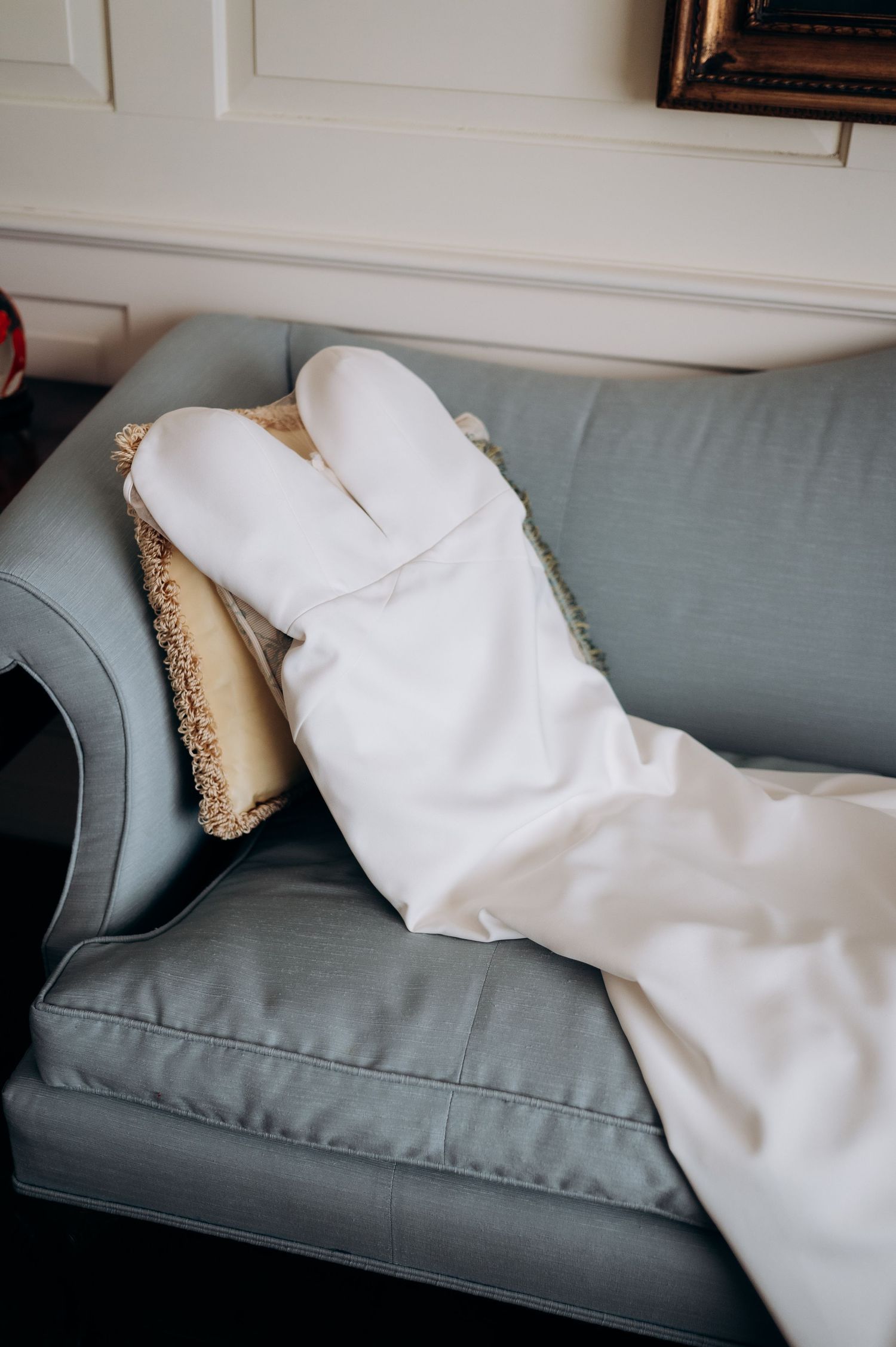 White fabric draped elegantly across a blue-gray couch in a minimalist setting.