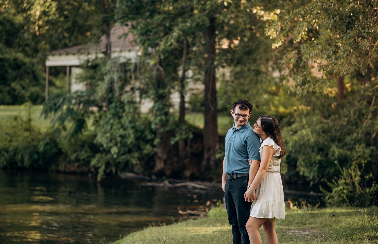 A couple shares an intimate moment during a lakeside engagement session at sunset.