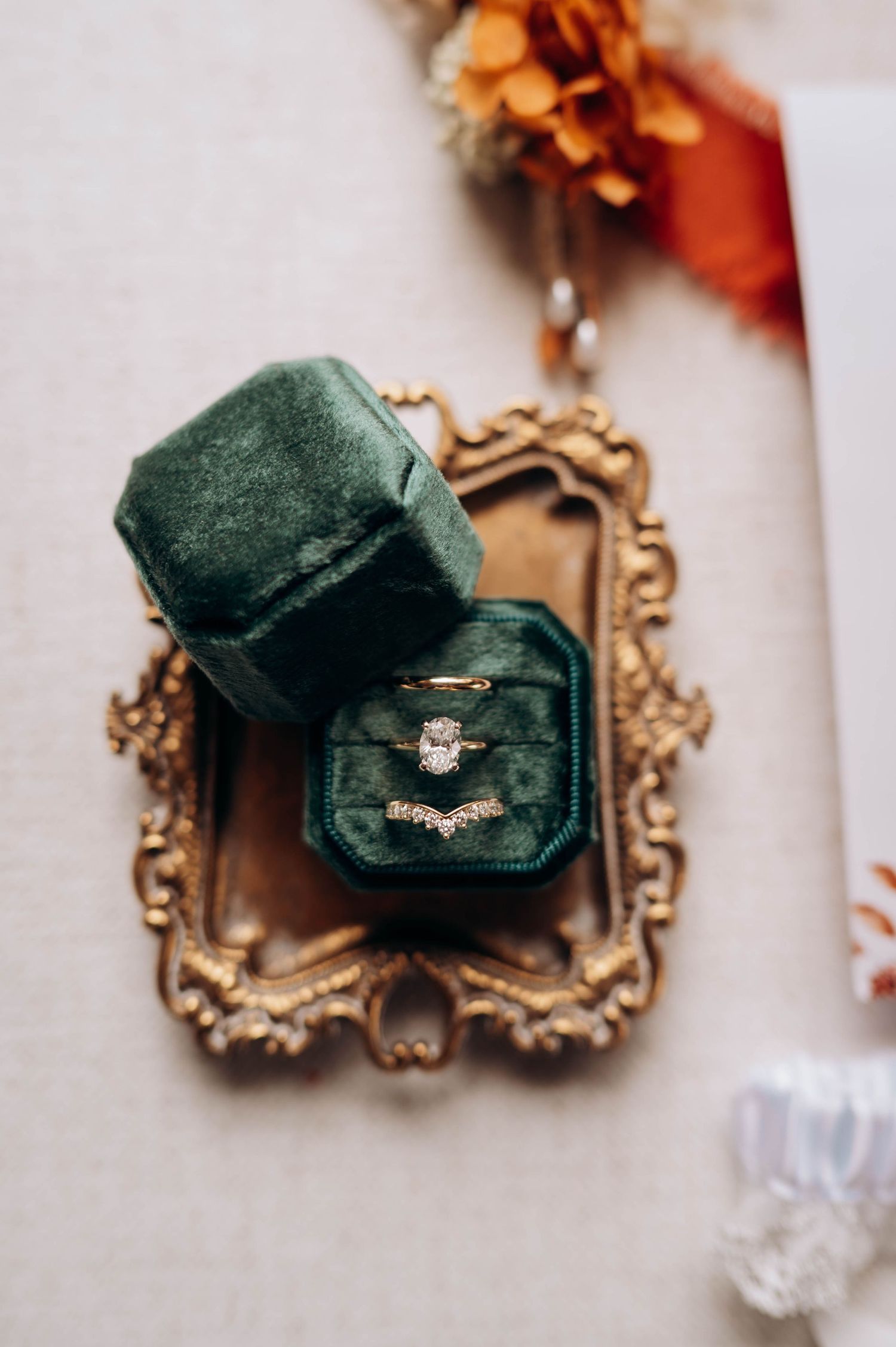 Vintage-style emerald velvet ring box displayed on ornate gold tray.
