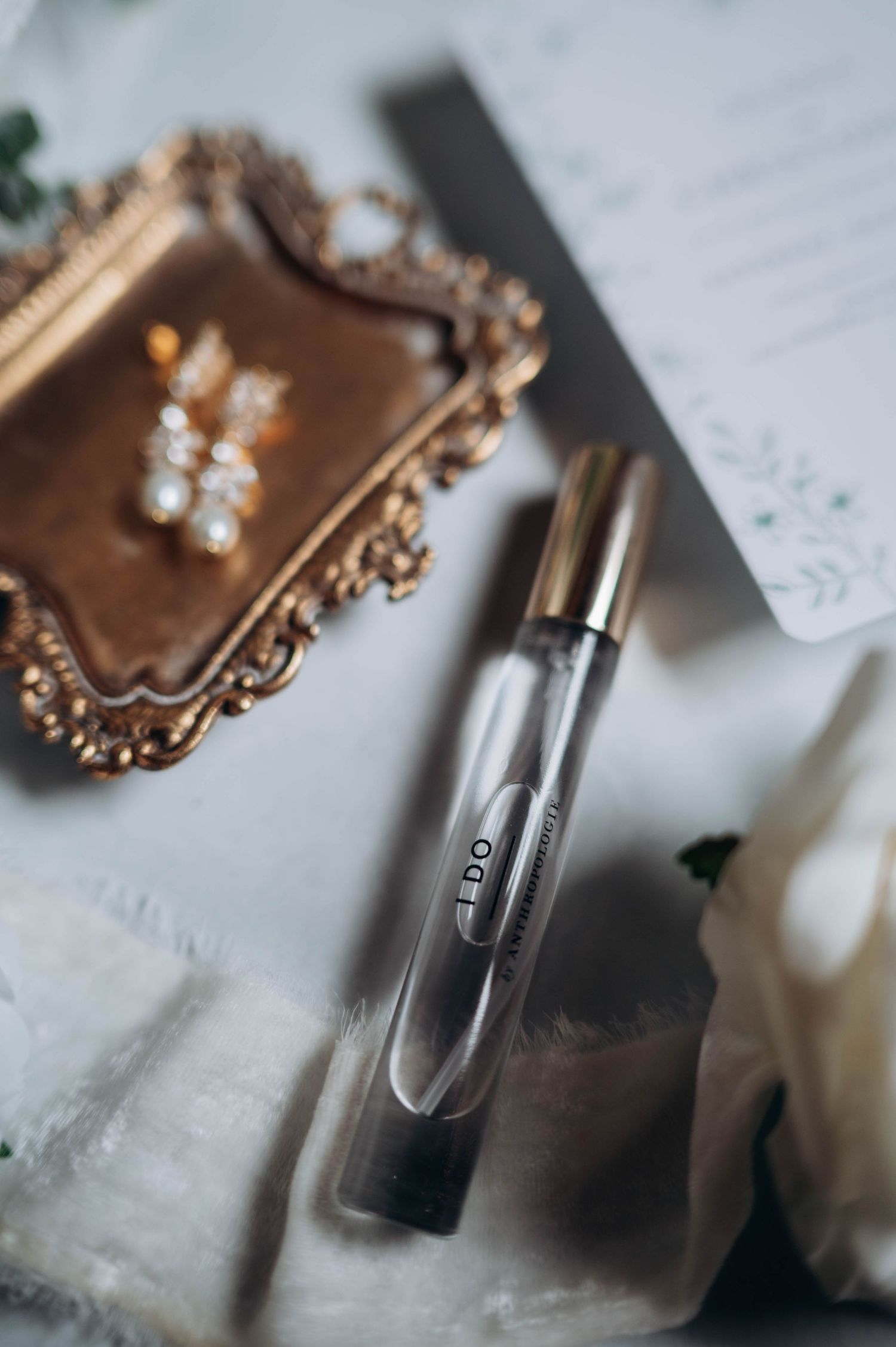 Close-up details of perfume bottles and wedding accessories on a white surface.