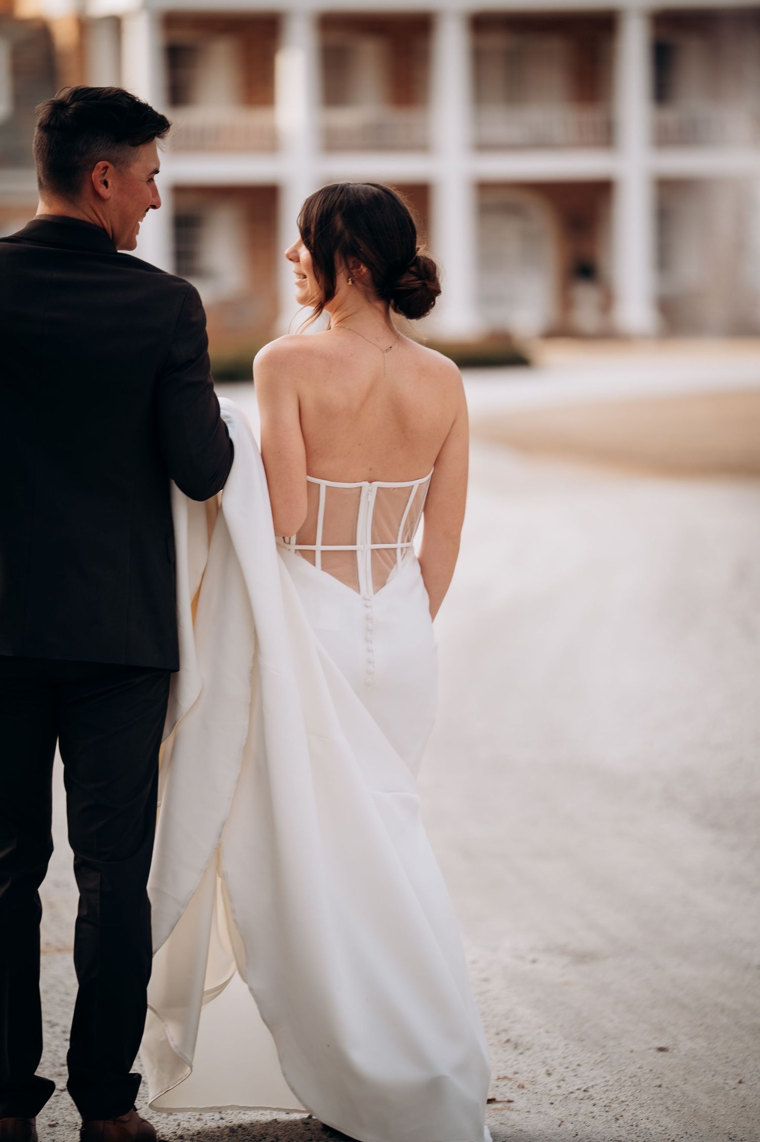 Elegant wedding dress details shown from behind against neutral background.
