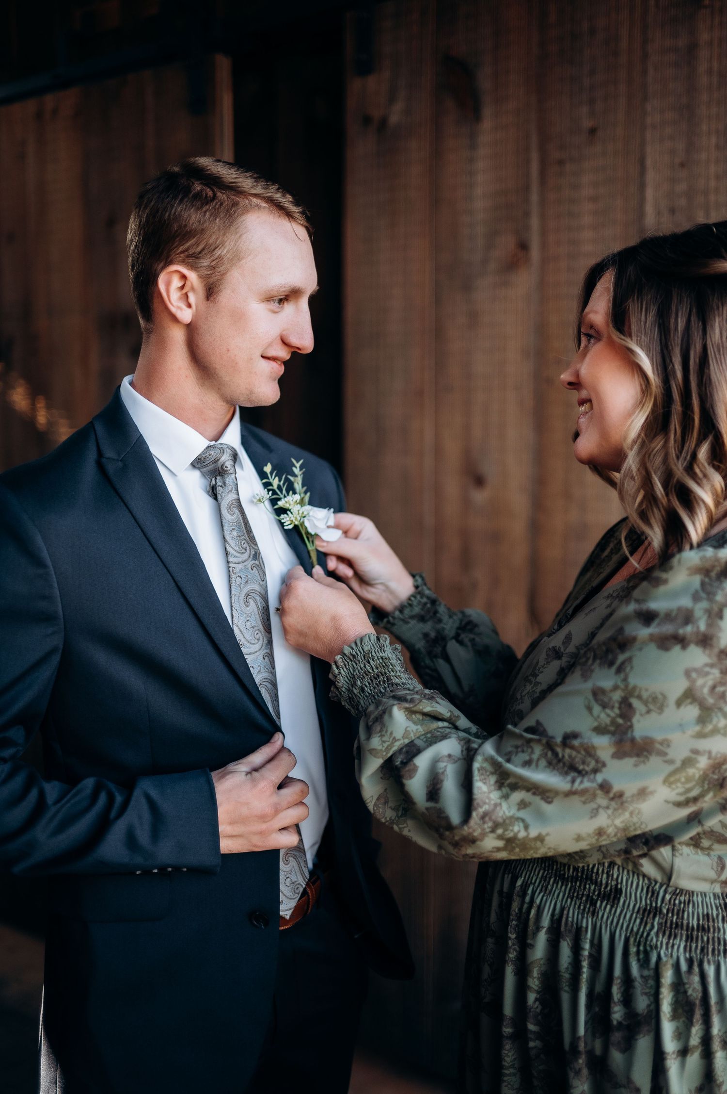 Intimate wedding preparation moment in rustic wooden setting.