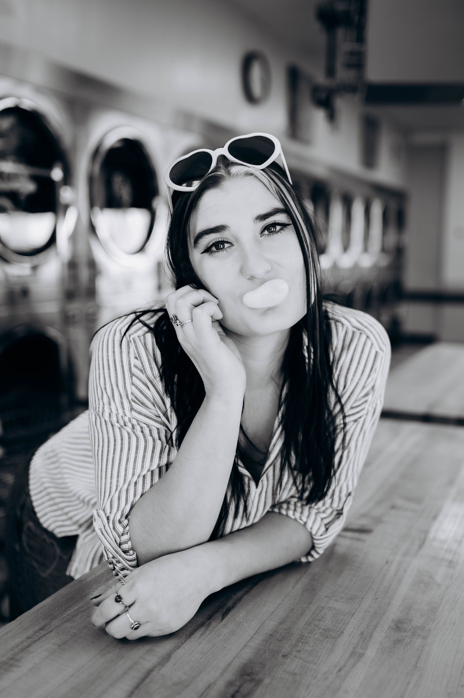 Black and white photo series of a person in striped shirt lying on wooden surface with retro sunglasses.