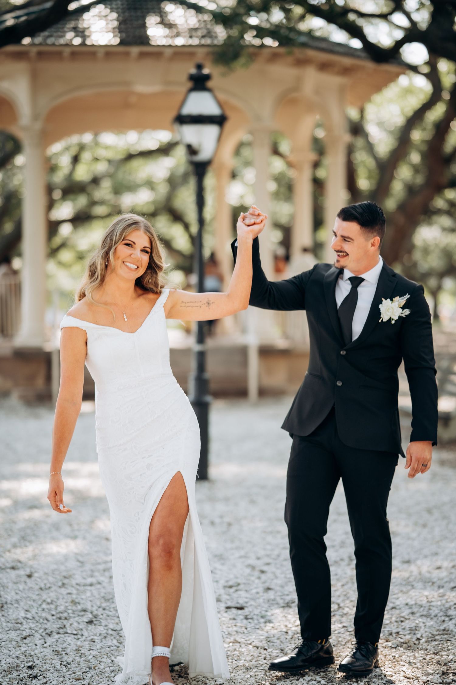 Joyful bride and groom celebrate after wedding ceremony under Spanish moss oak trees in park.