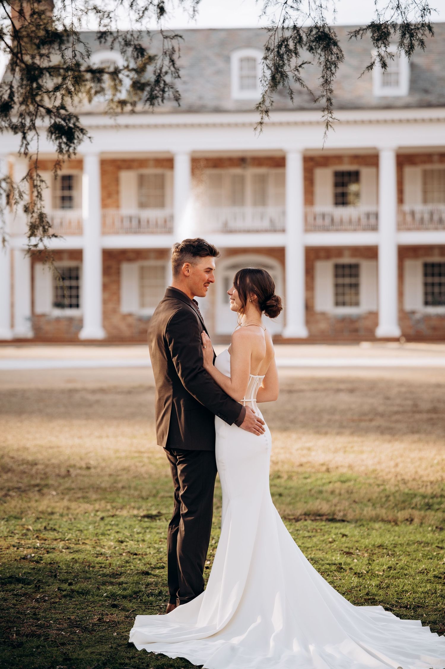 Elegant couple poses in front of a historic colonial-style building with white columns.