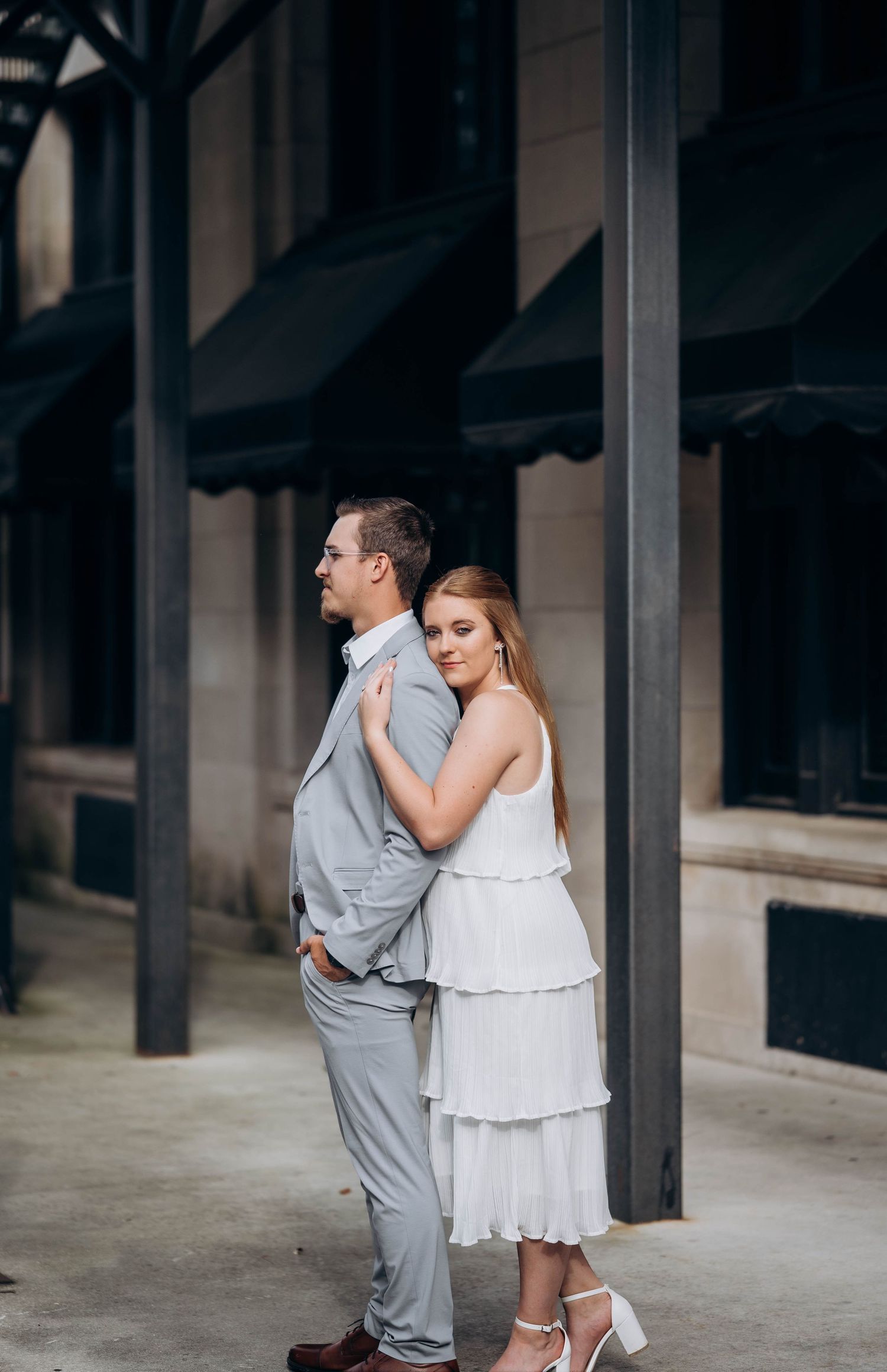 A tender moment shared between a couple under a covered walkway with dark columns.