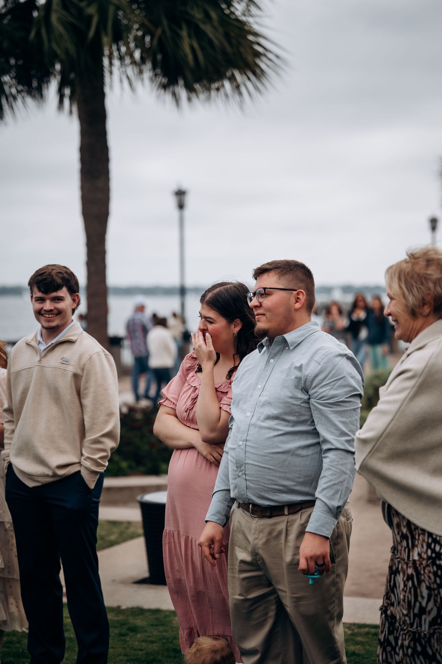 Wedding guests watching an emotional ceremony under palm trees.