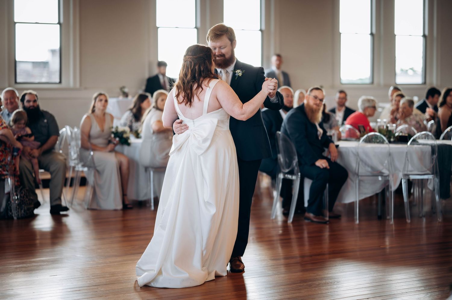Couple performing an elegant dance move during their wedding reception in a bright ballroom.