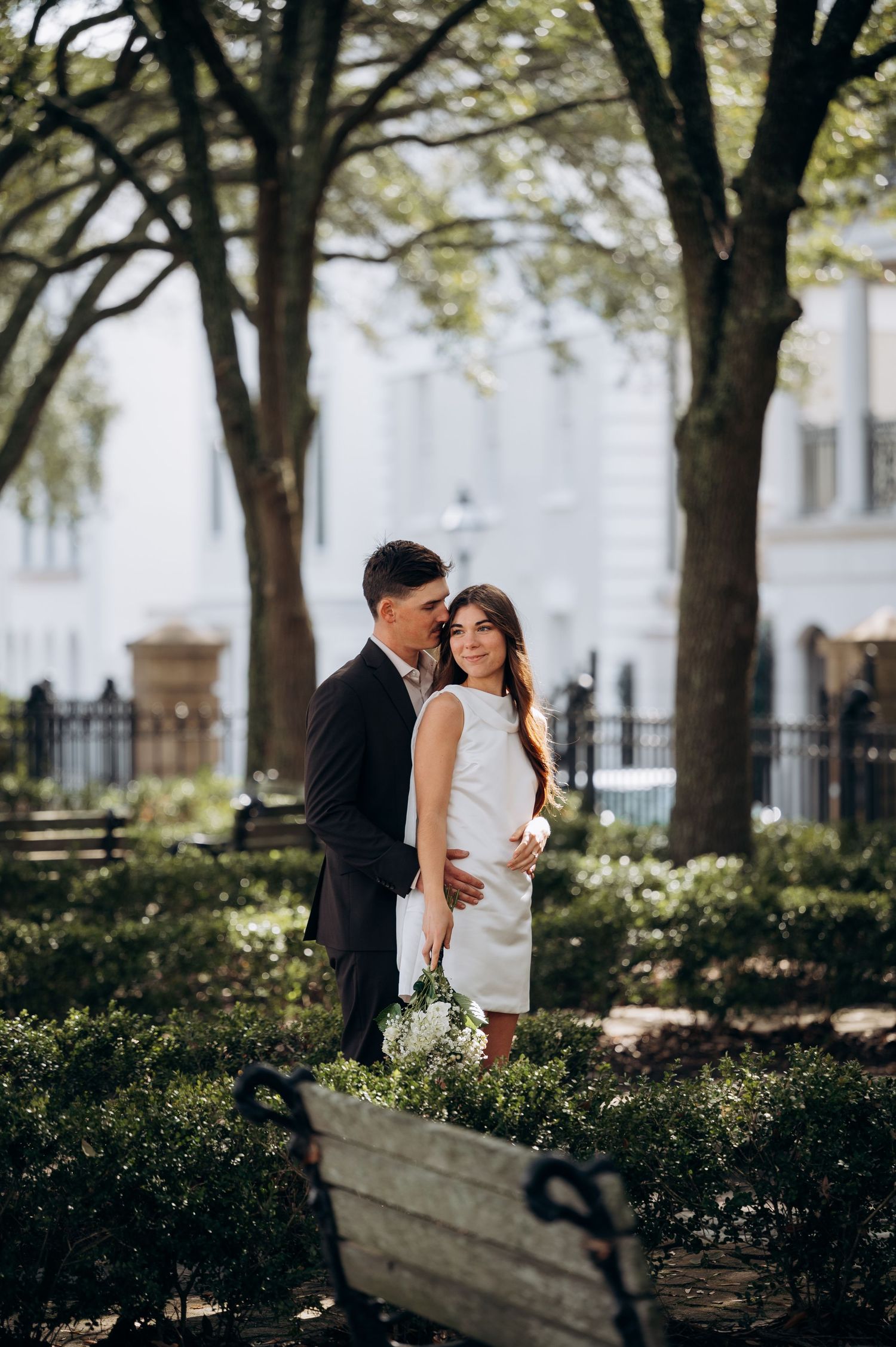 Couple sharing romantic moments in a tree-lined garden pathway.