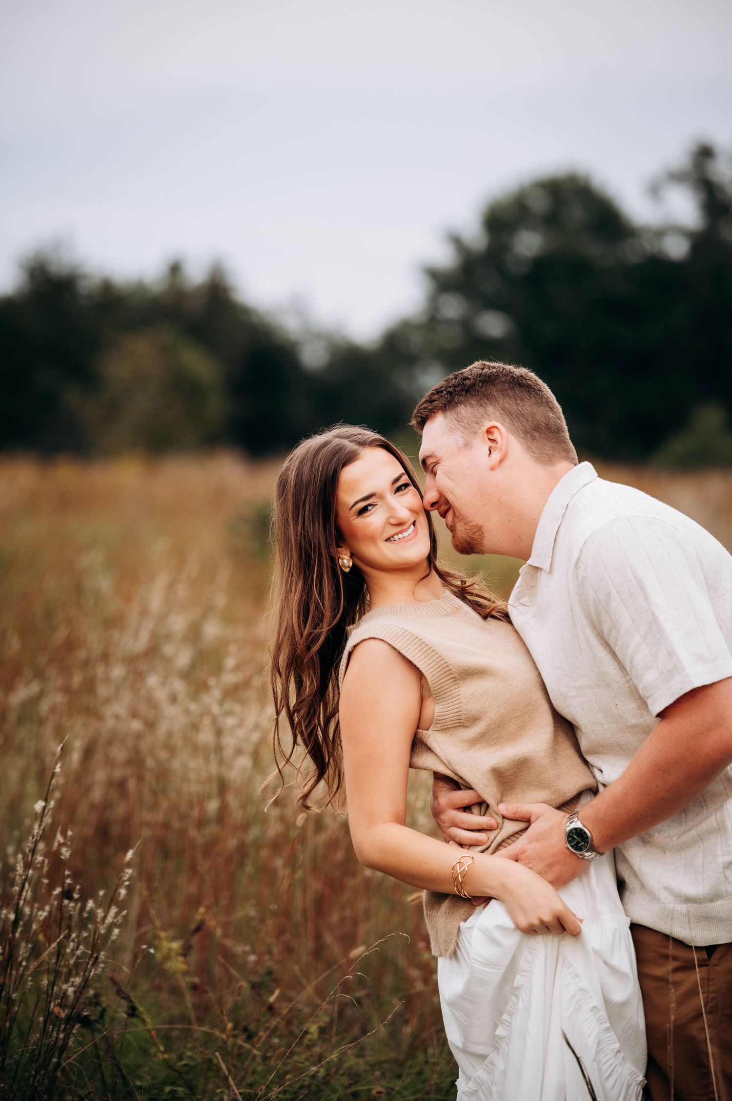 Romantic couple shares intimate moments in a rustic field of tall grass during golden hour photoshoot.