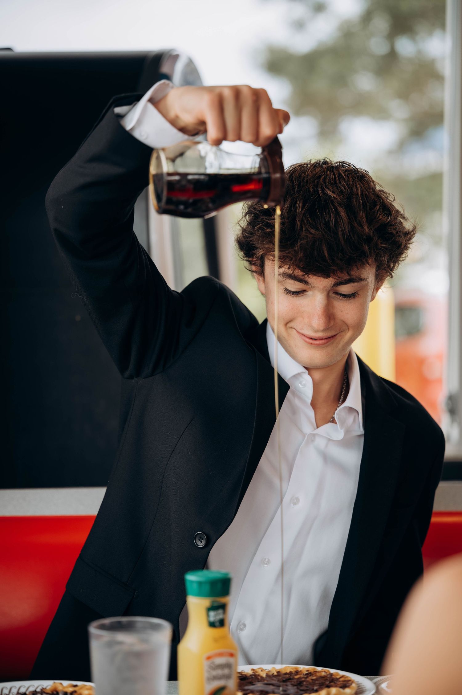 Person in formal attire pouring syrup on breakfast food at Waffle House.