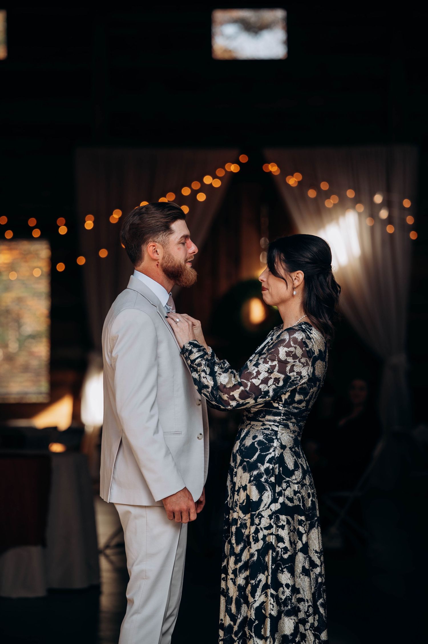 Wedding dance scene with a couple in formal attire under warm string lights.