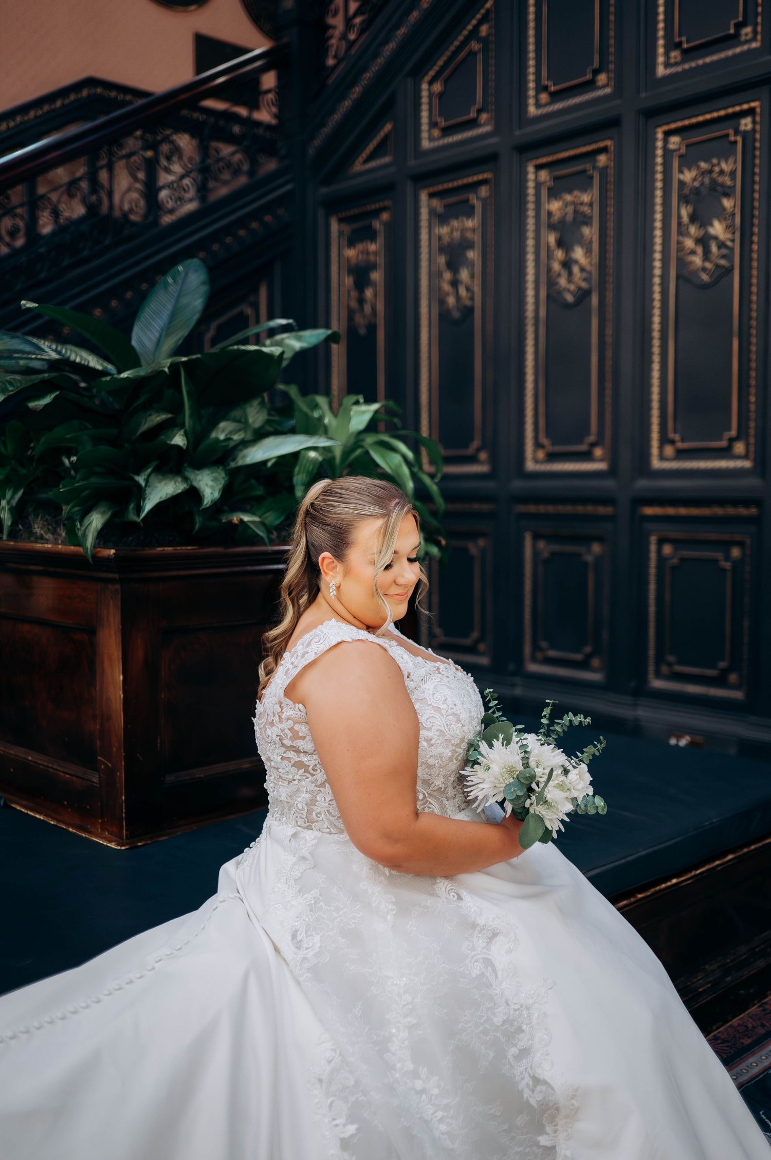 Back detail of bride's lace wedding dress against elegant dark interior.